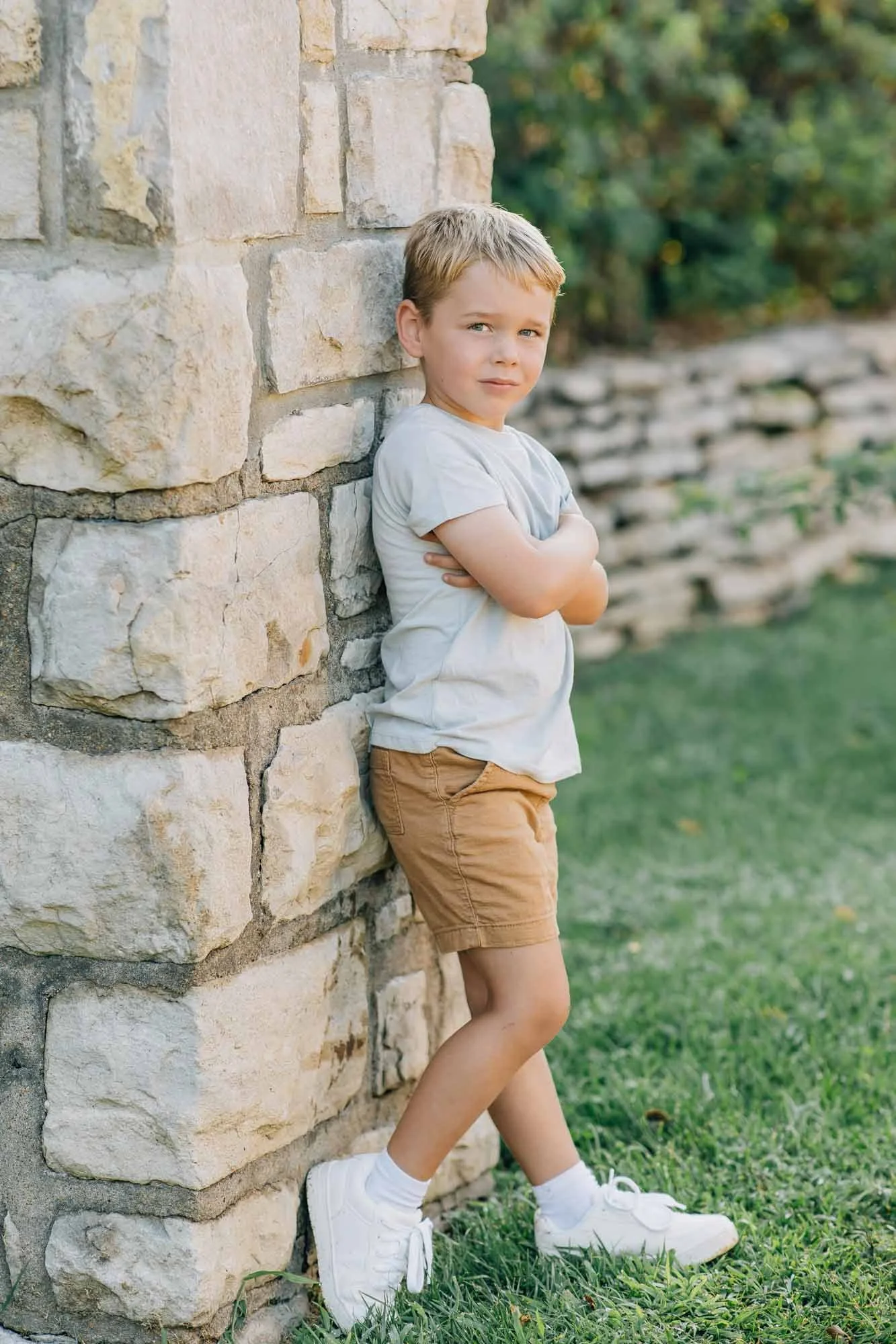 little boy smiling and posing near a pillar