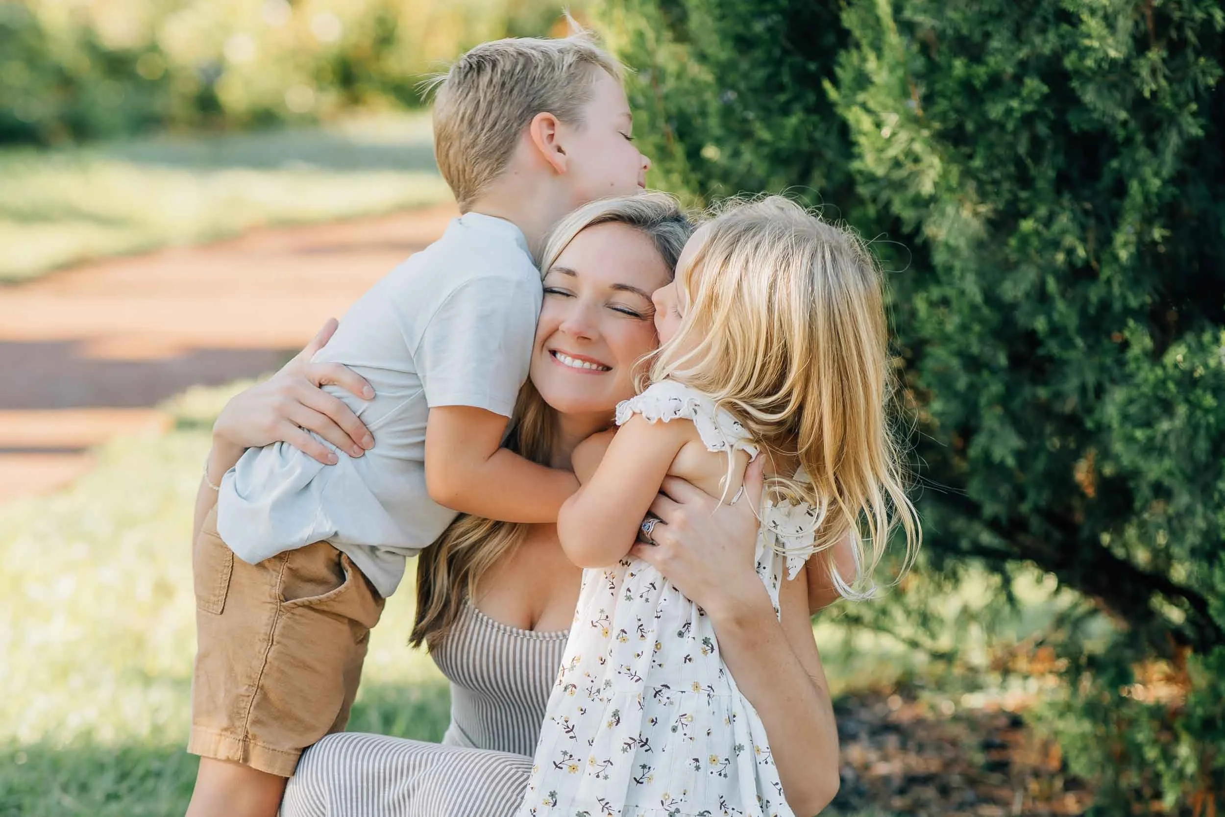 mom hugging son and daughter in a garden park