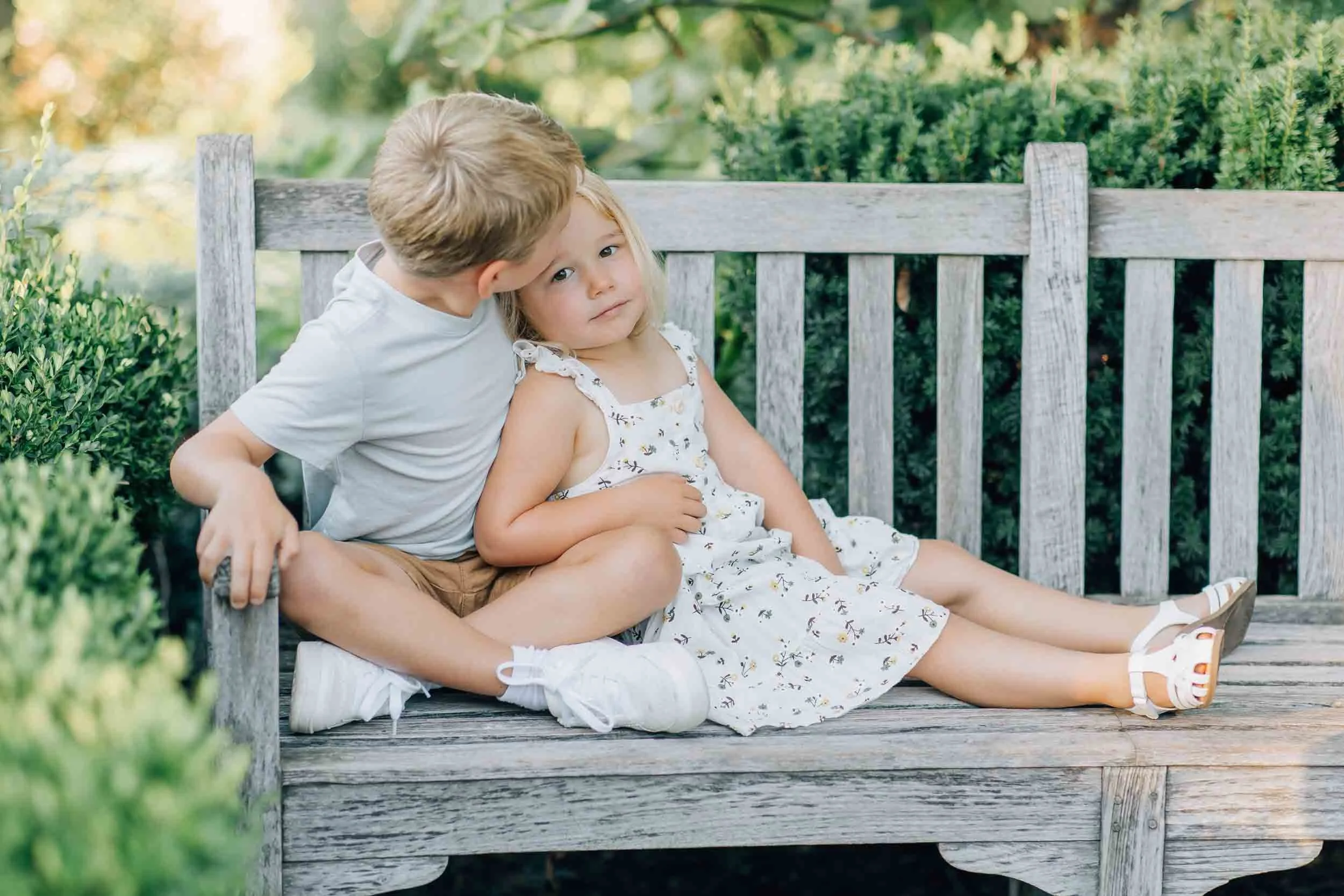 Brother and sister sitting on a bench in the park