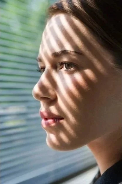 Ragazza con luce e ombre di strisce sui volti, con sfondo sfocato e luci naturali.
