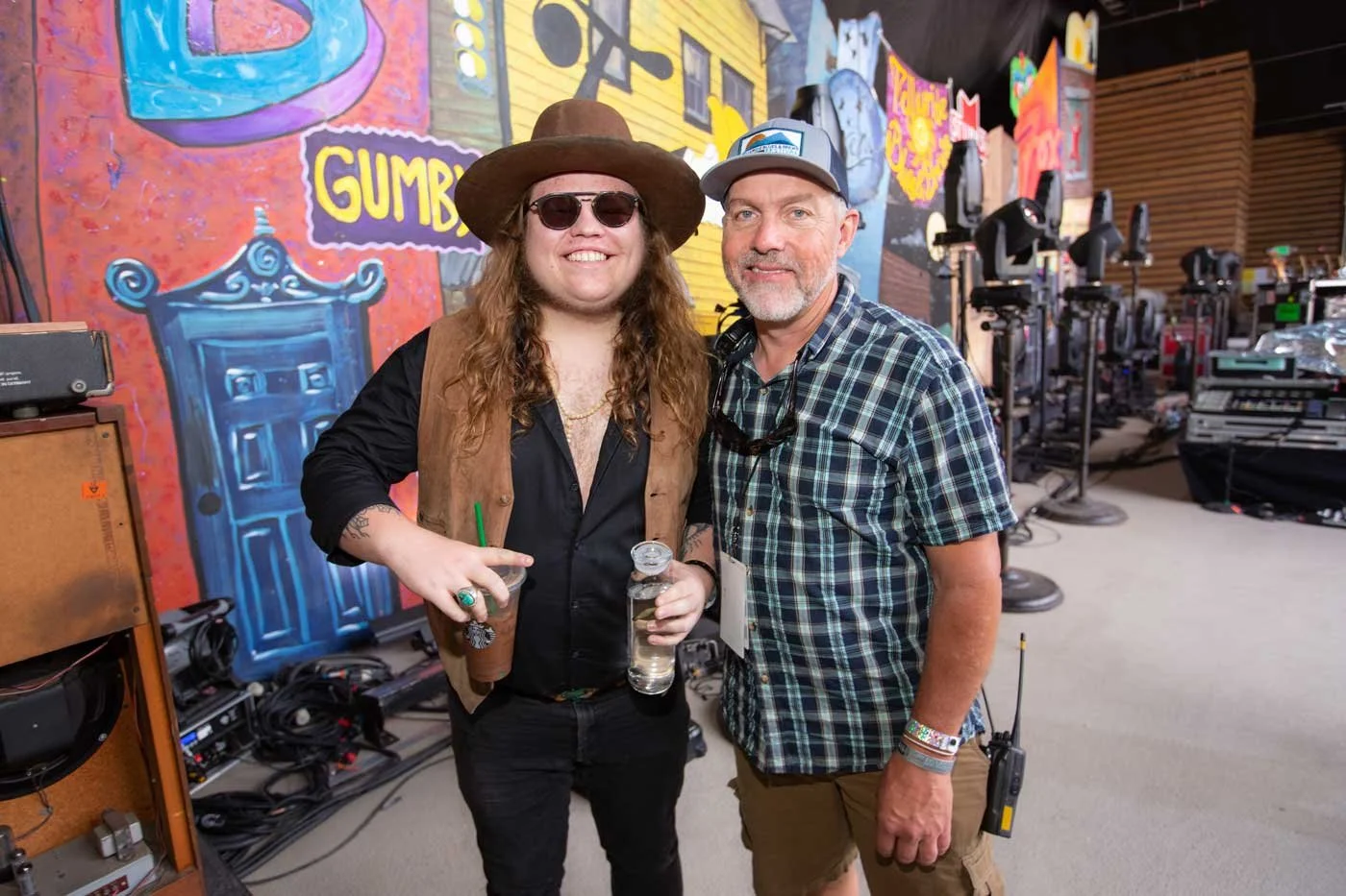 Steve Gumble and Marcus King stand together on the side stage during the Telluride Blues & Brews Festival, with the Main Stage performance in the background and festival attendees filling Town Park beneath the scenic San Juan Mountains.