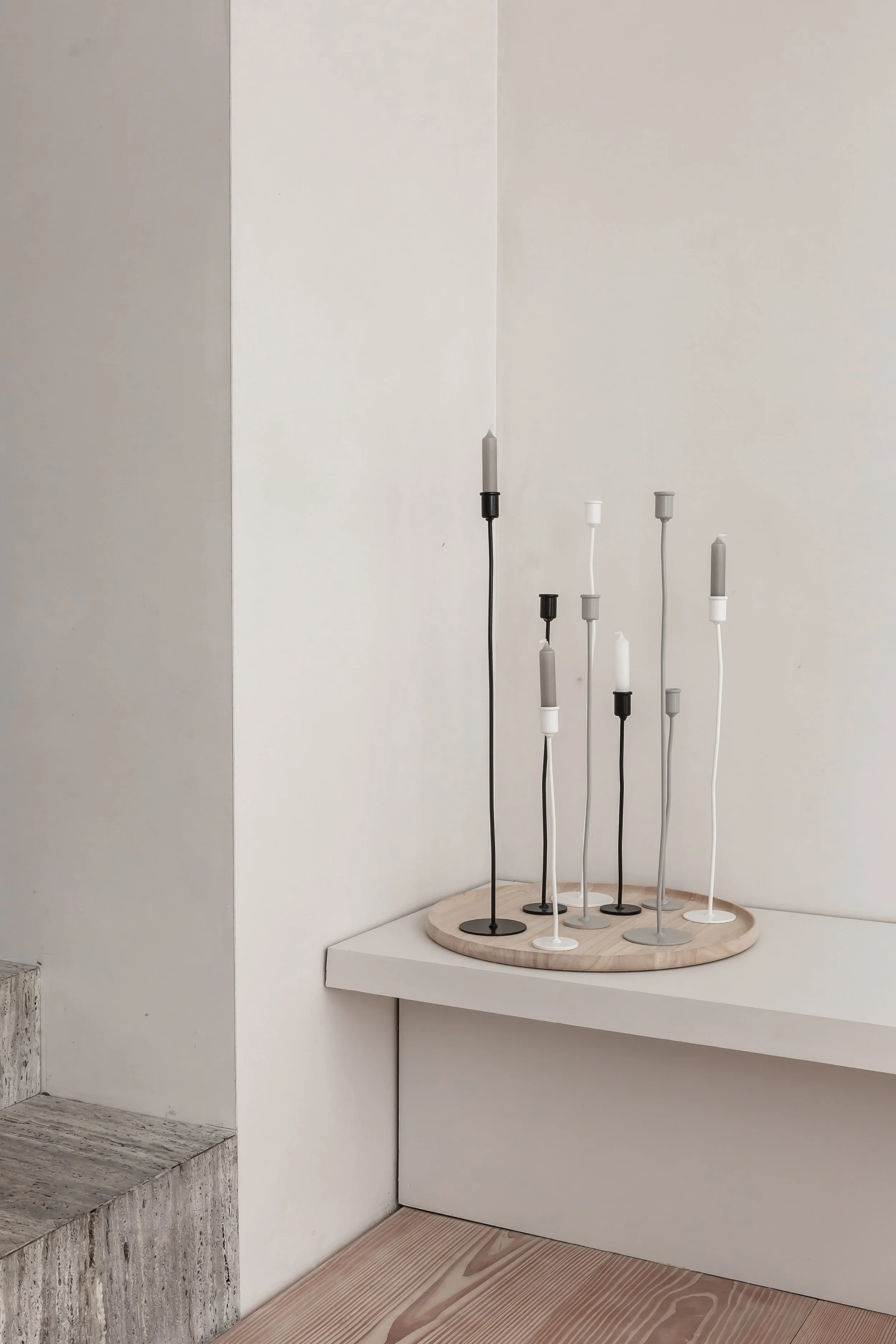 Minimalist modern candleholders with slim candles on a round wooden base
