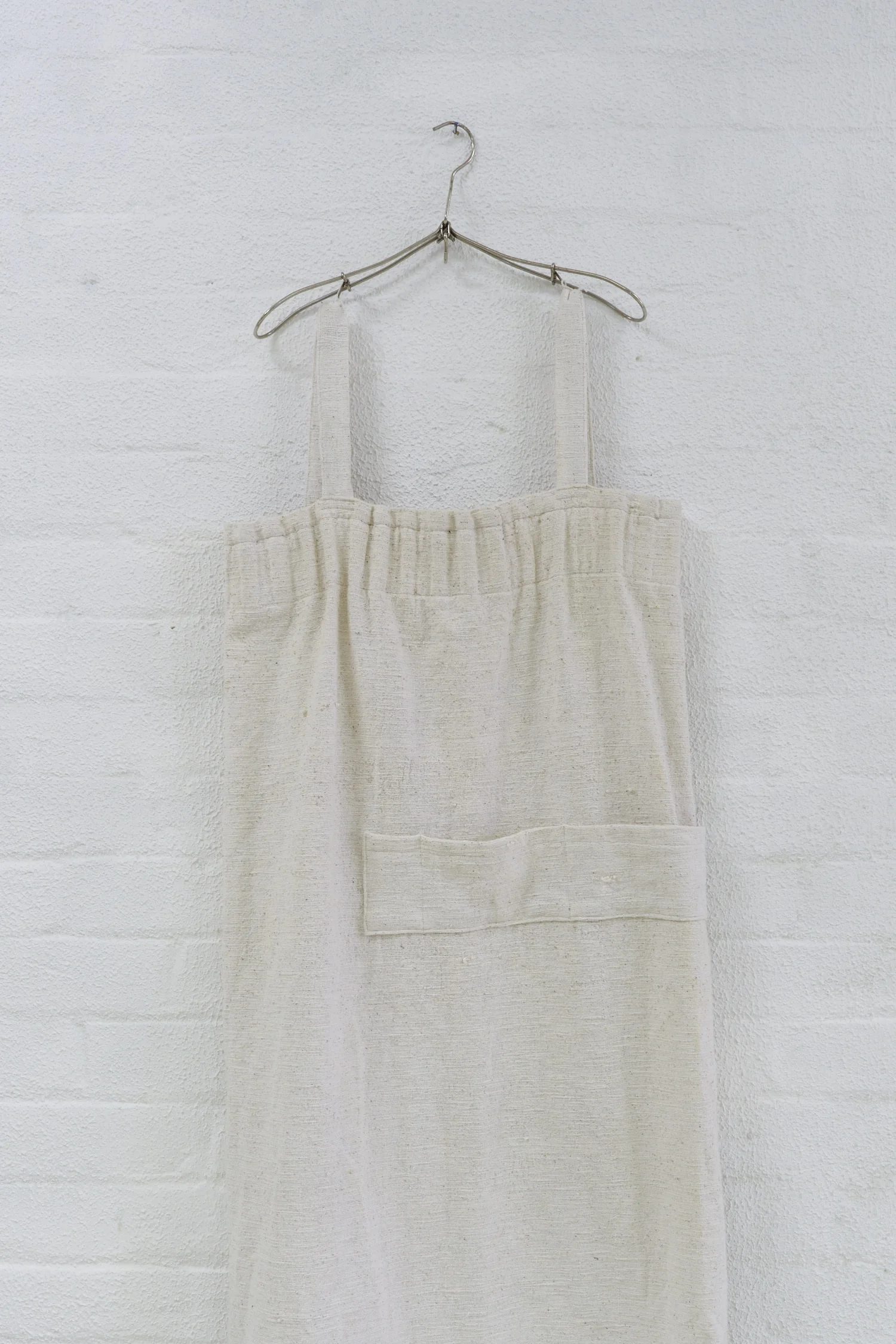 Bridget Currie, A hanger from my collection (folding metal wire hanger). Metal. Origin & year unknown. This hanger was nestled in the rack shouldering a pinafore (pictured) by Angela Carrig.