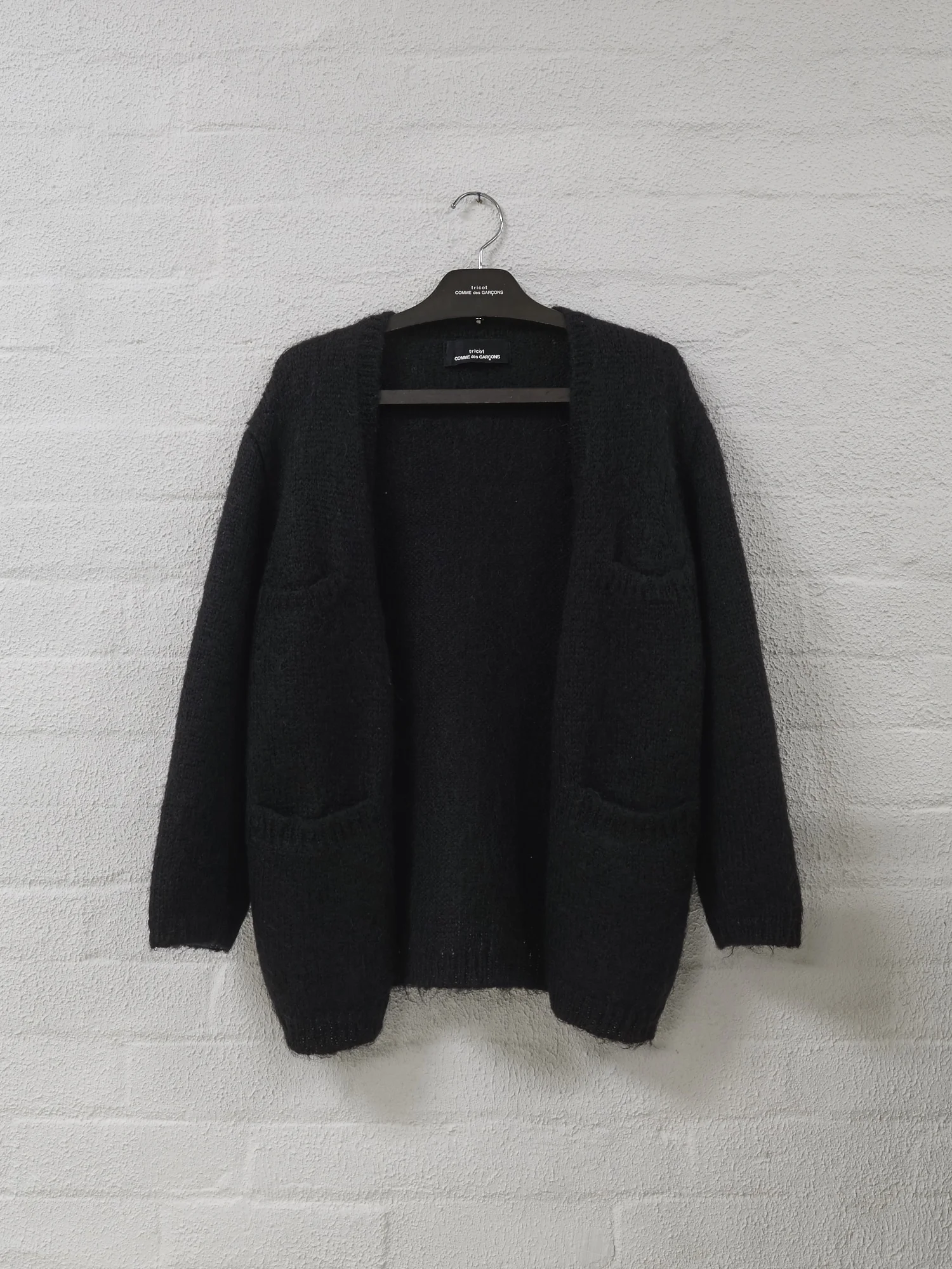 Filter Store, Tricot Comme des Garcons brown wooden hanger, c.1980s with a Comme wool cardigan. This hanger was nestled on the racks for ‘hangers’, here its hanging on the wall.