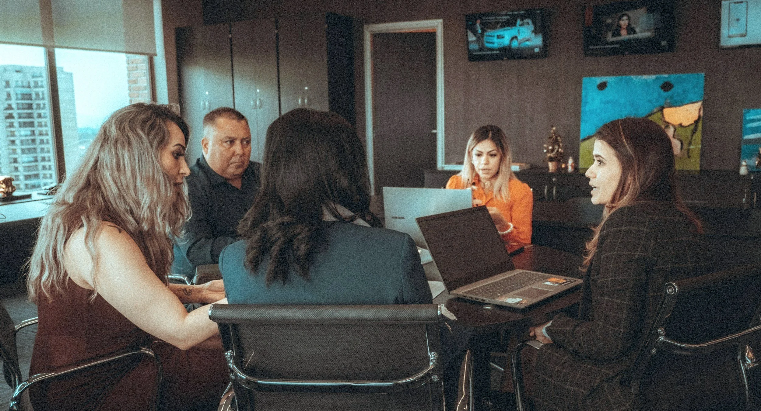 People sitting around a table with laptops open.