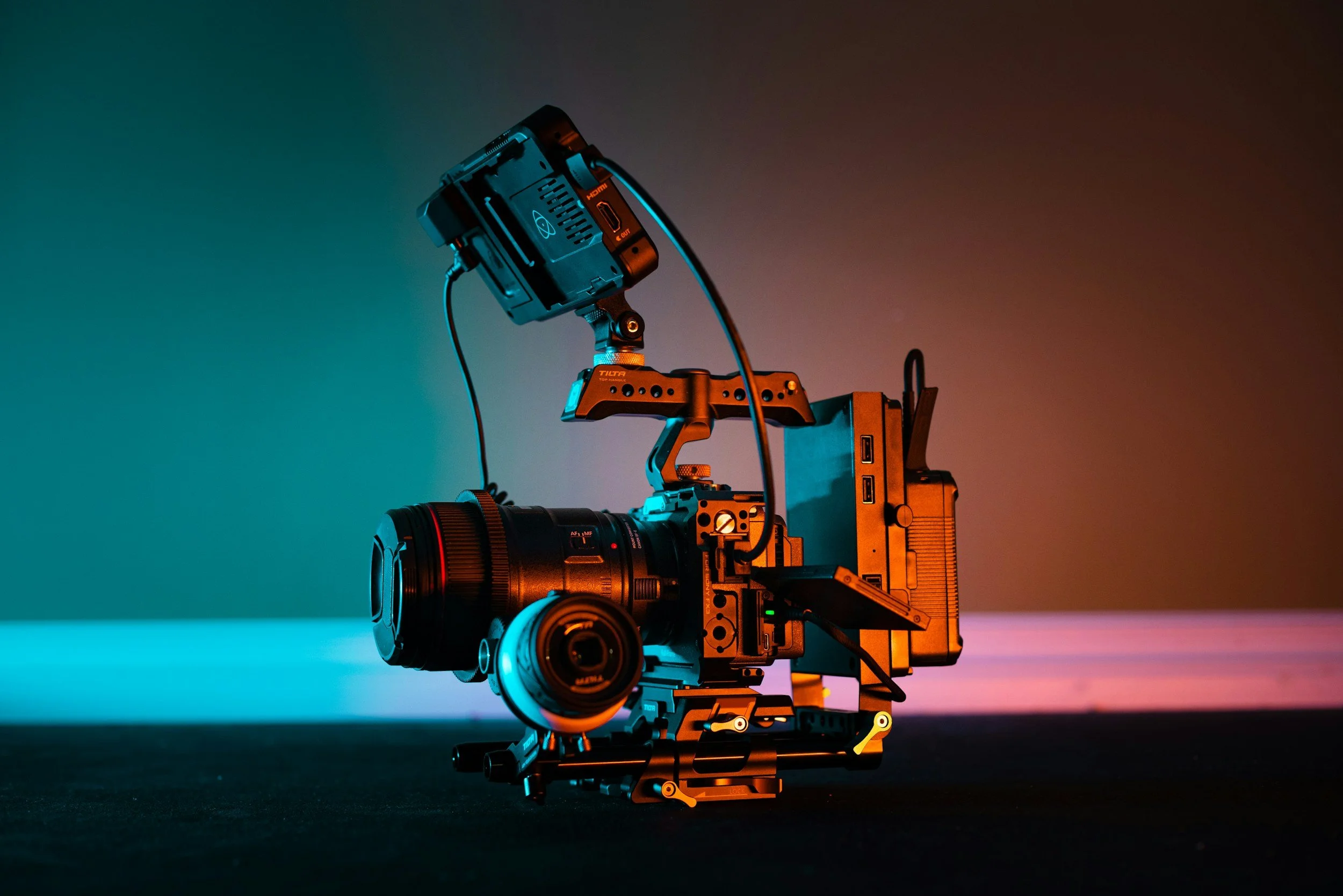 Camera attached to a stabilizer rig in a low-light setting with colorful backlighting.