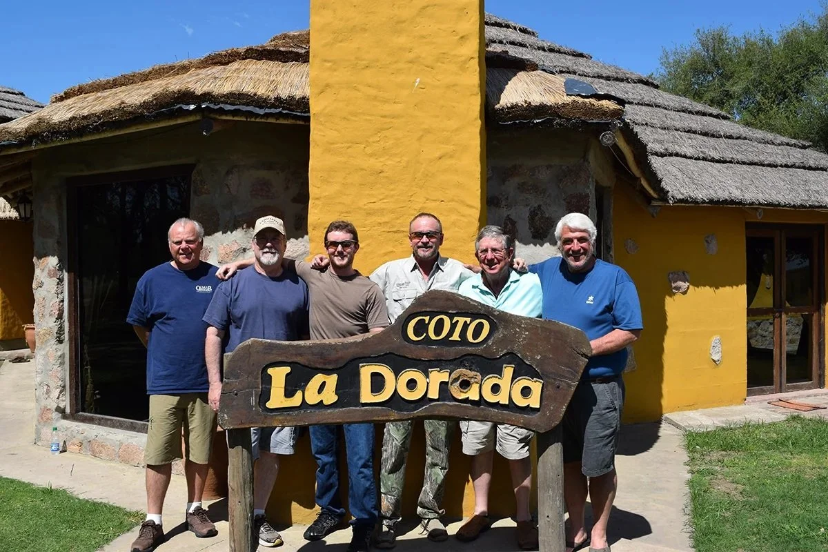 Group of people standing outside La Dorada restaurant holding a sign in front of the building.