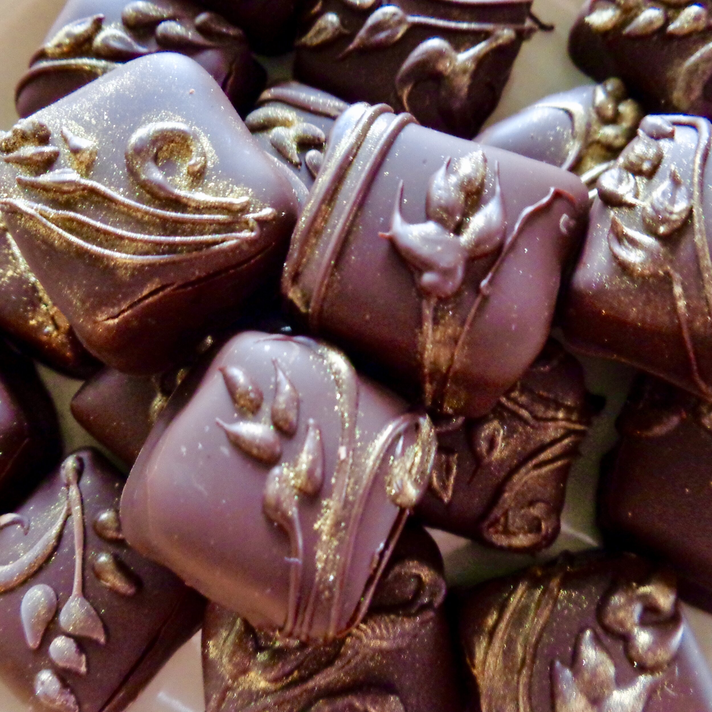 Henna-adorned dark chocolate truffles with gold luster.