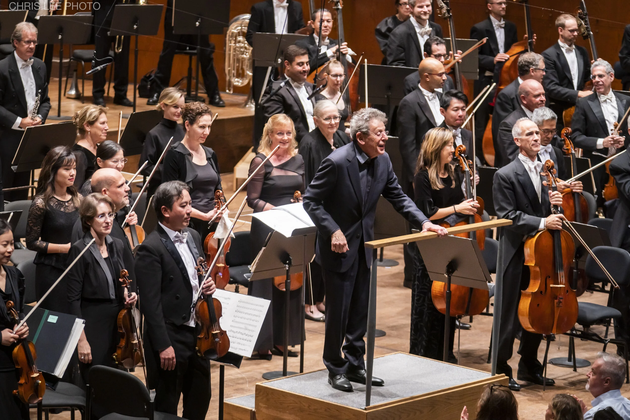 Philip Glass takes a bow with members of the New York Philharmonic. Photo by Chris Lee.