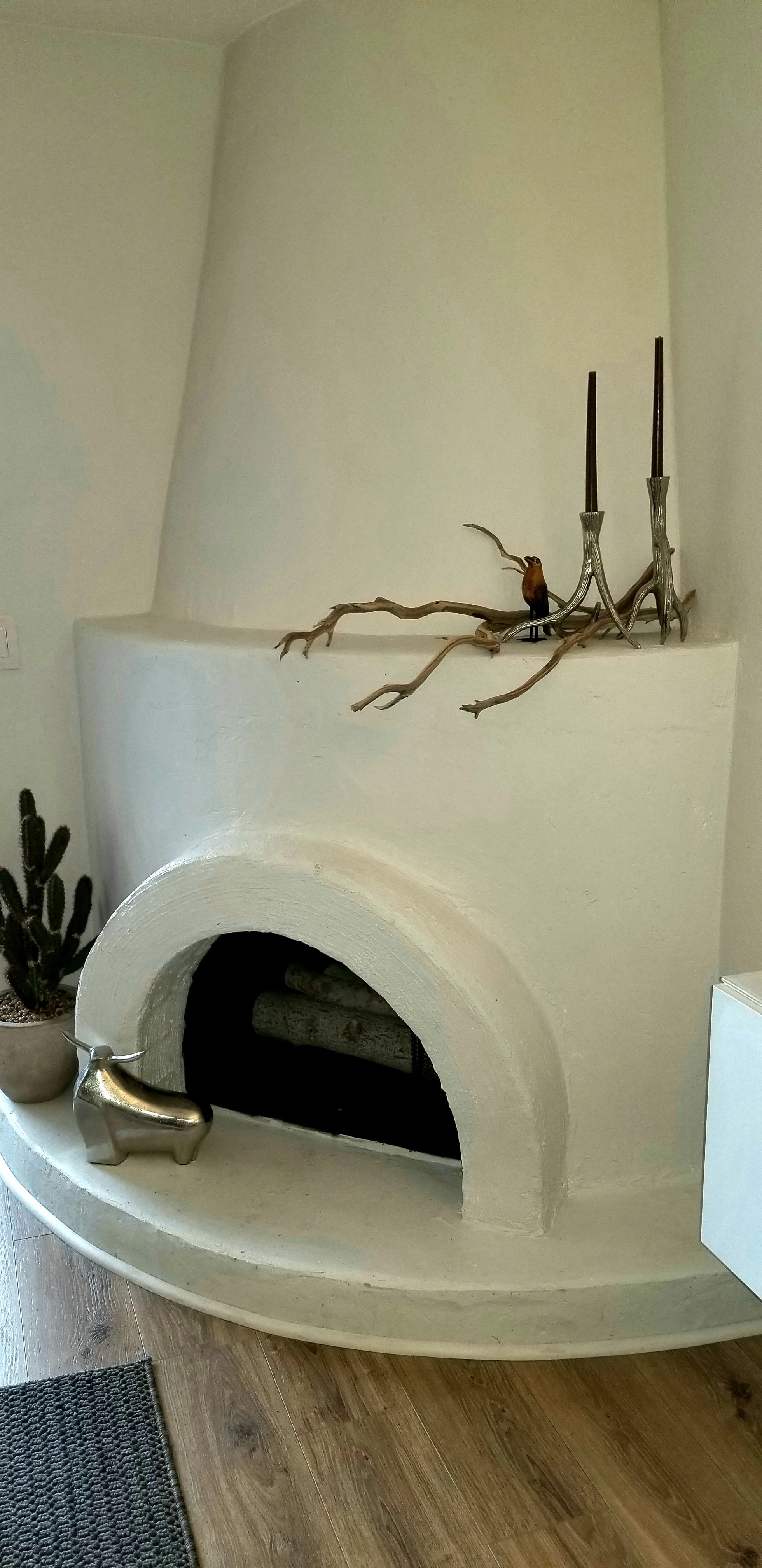 This classic beehive fireplace adorns the room opposite the seating area. Simple accessories balance out the vertical element.