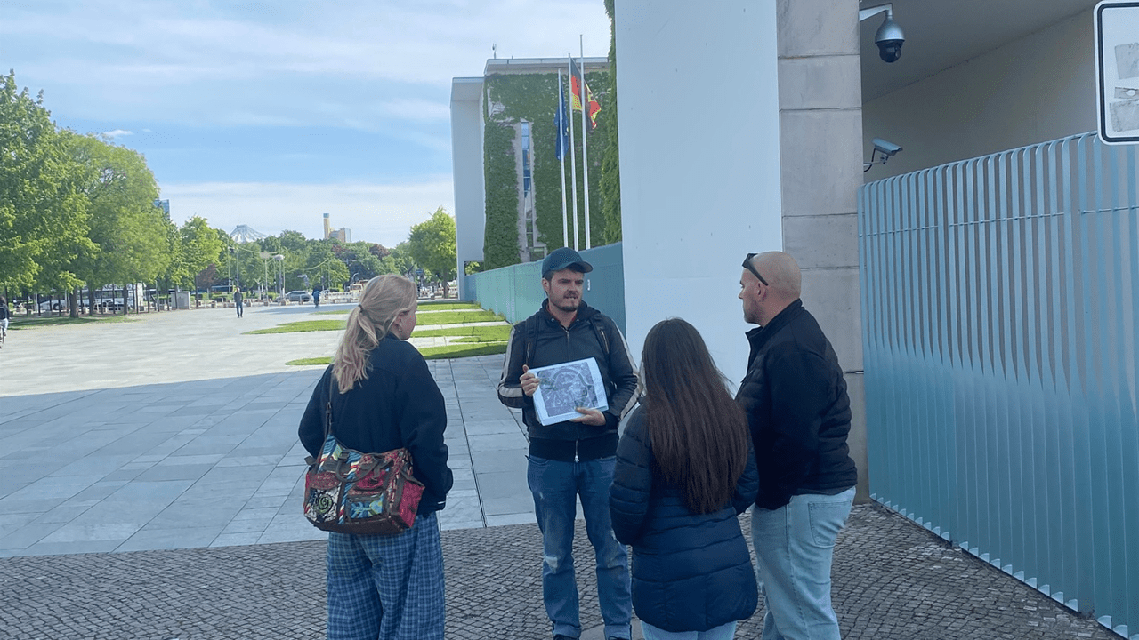 A specialist military historian briefs a tour group with battle maps in front of the Reichstag
