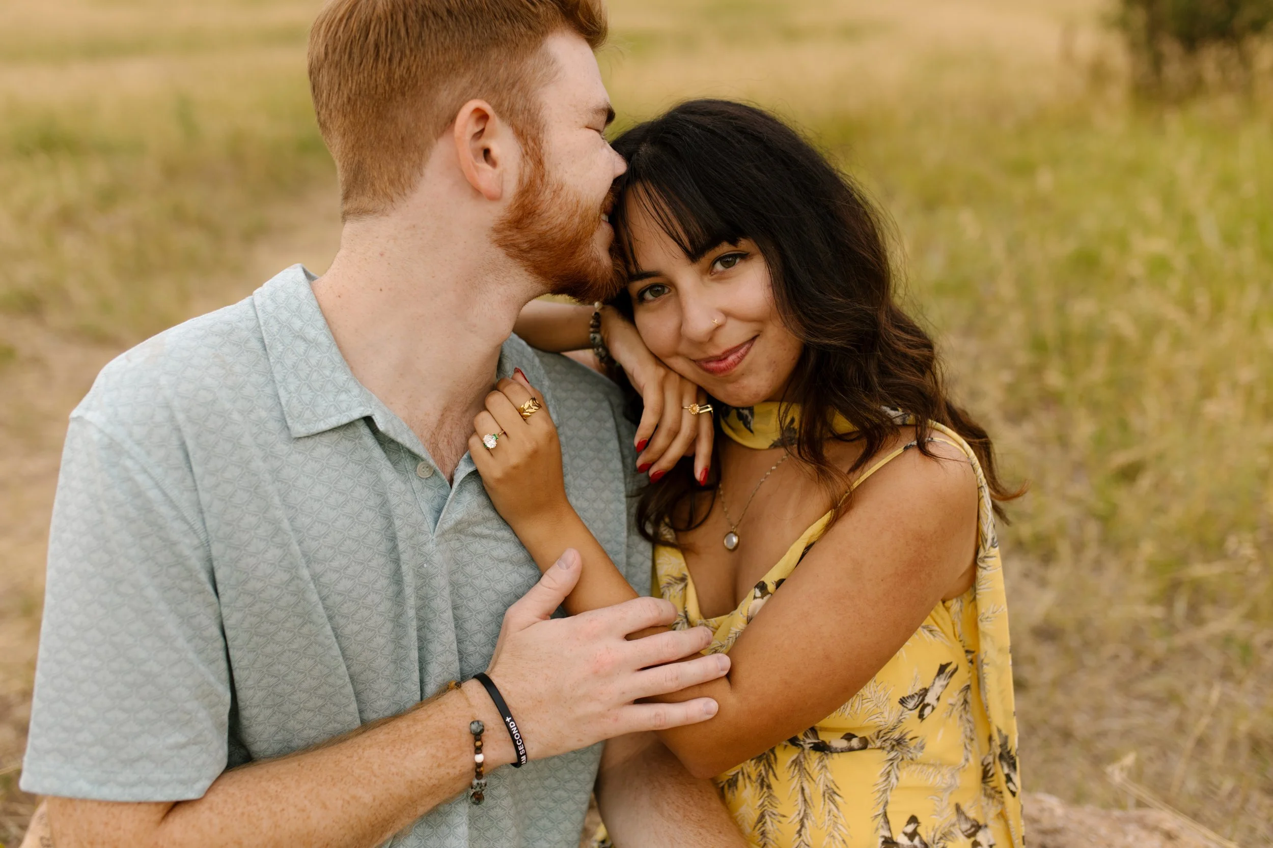 Close-up portrait of an engaged couple, Nadja smiling softly while holding Garrison, showing off her ring.