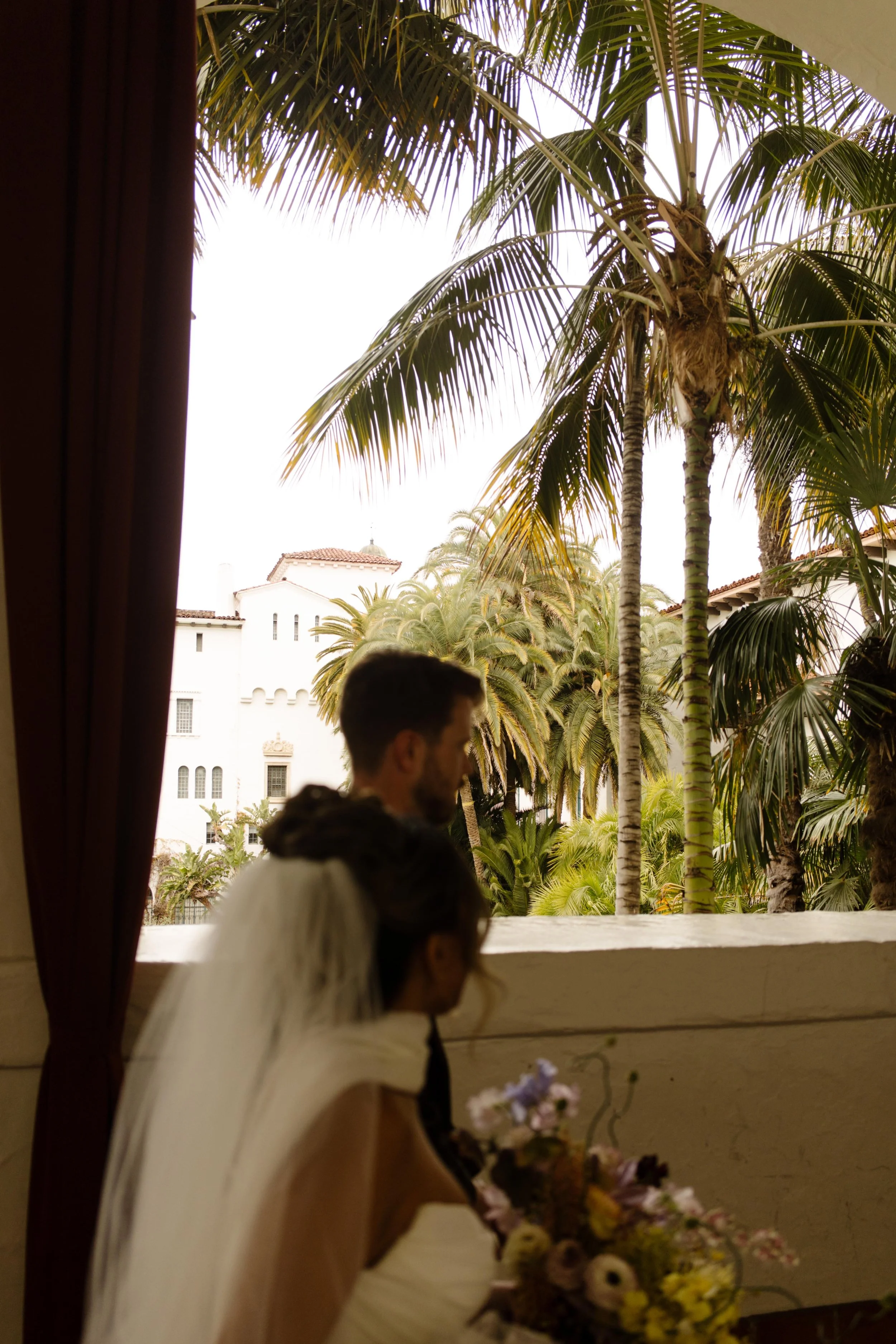 The couple gazes out at the palm tree-lined view from one of the balconies of the Santa Barbara Courthouse.