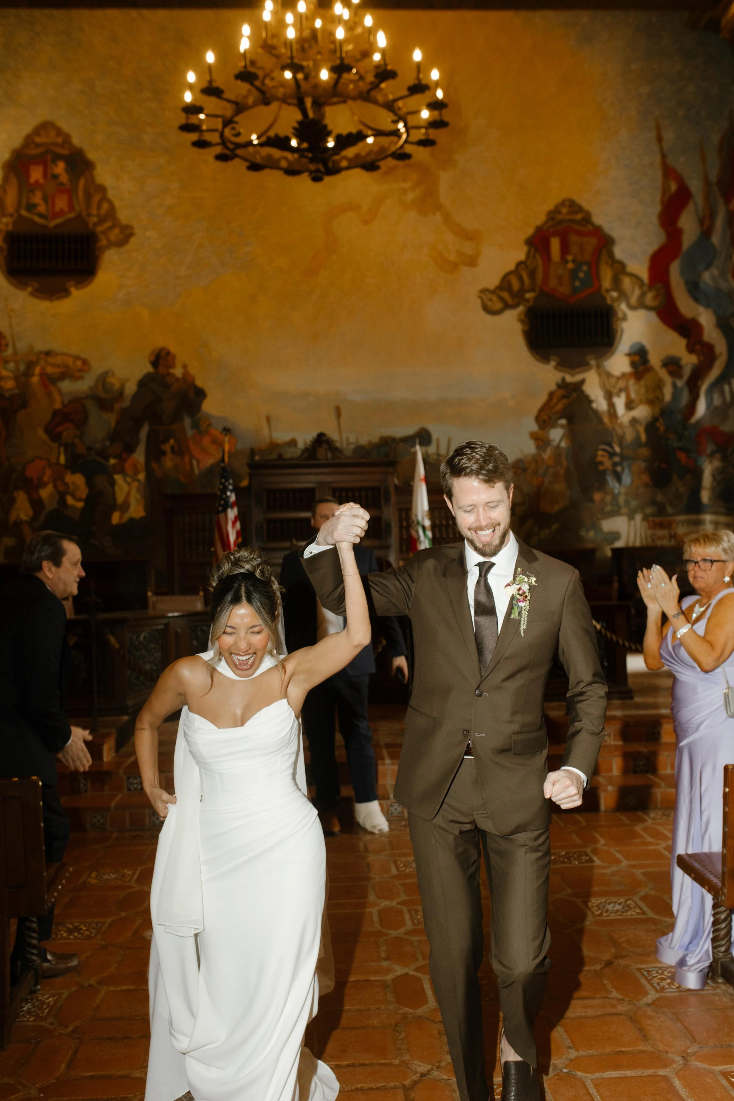 Just married and full of giddy energy, the couple walks out hand in hand during their wedding Santa Barbara Courthouse ceremony exit.