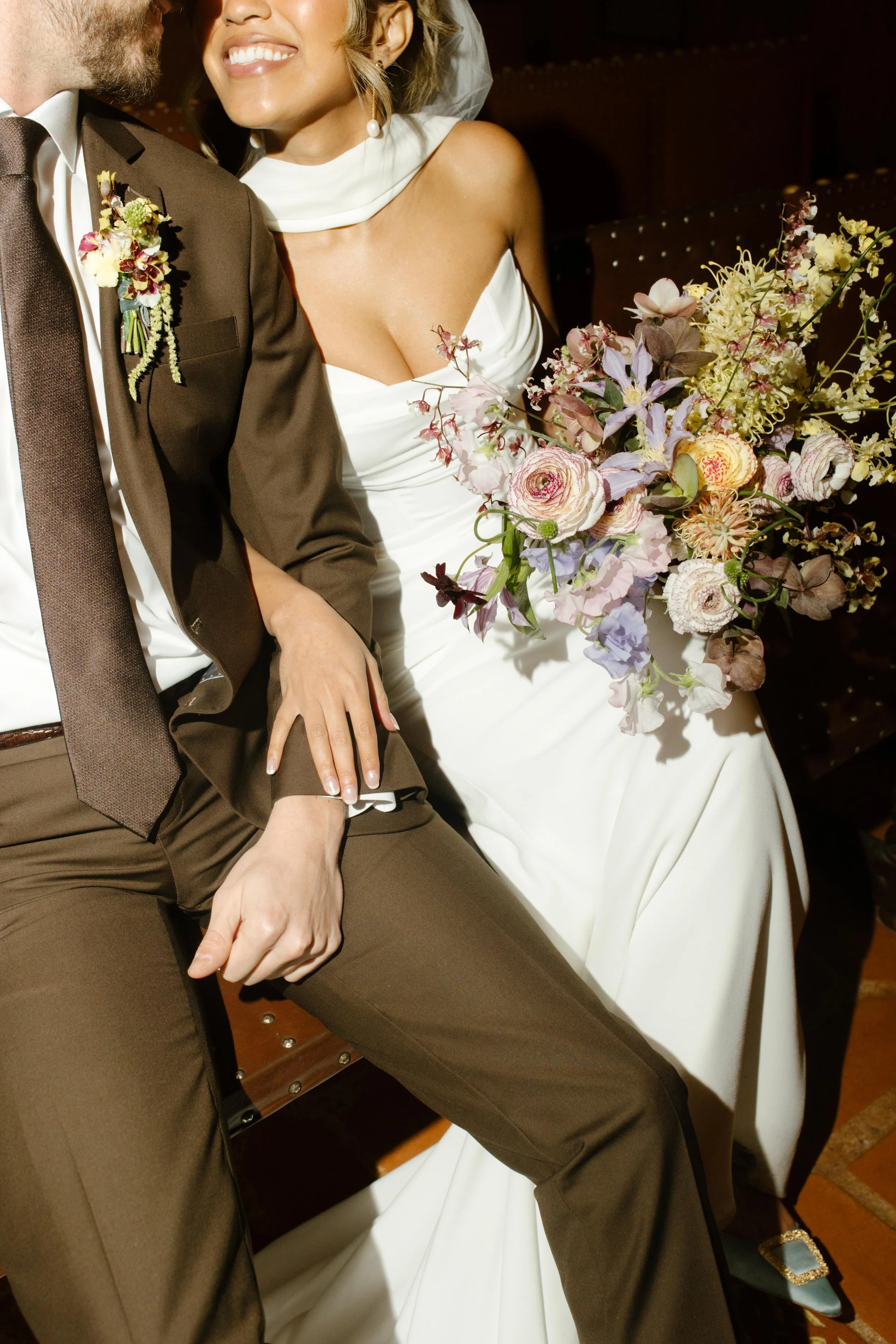 A close-up of the bride’s bouquet and the couple’s hands—warm tones and soft petals at their wedding Santa Barbara Courthouse.