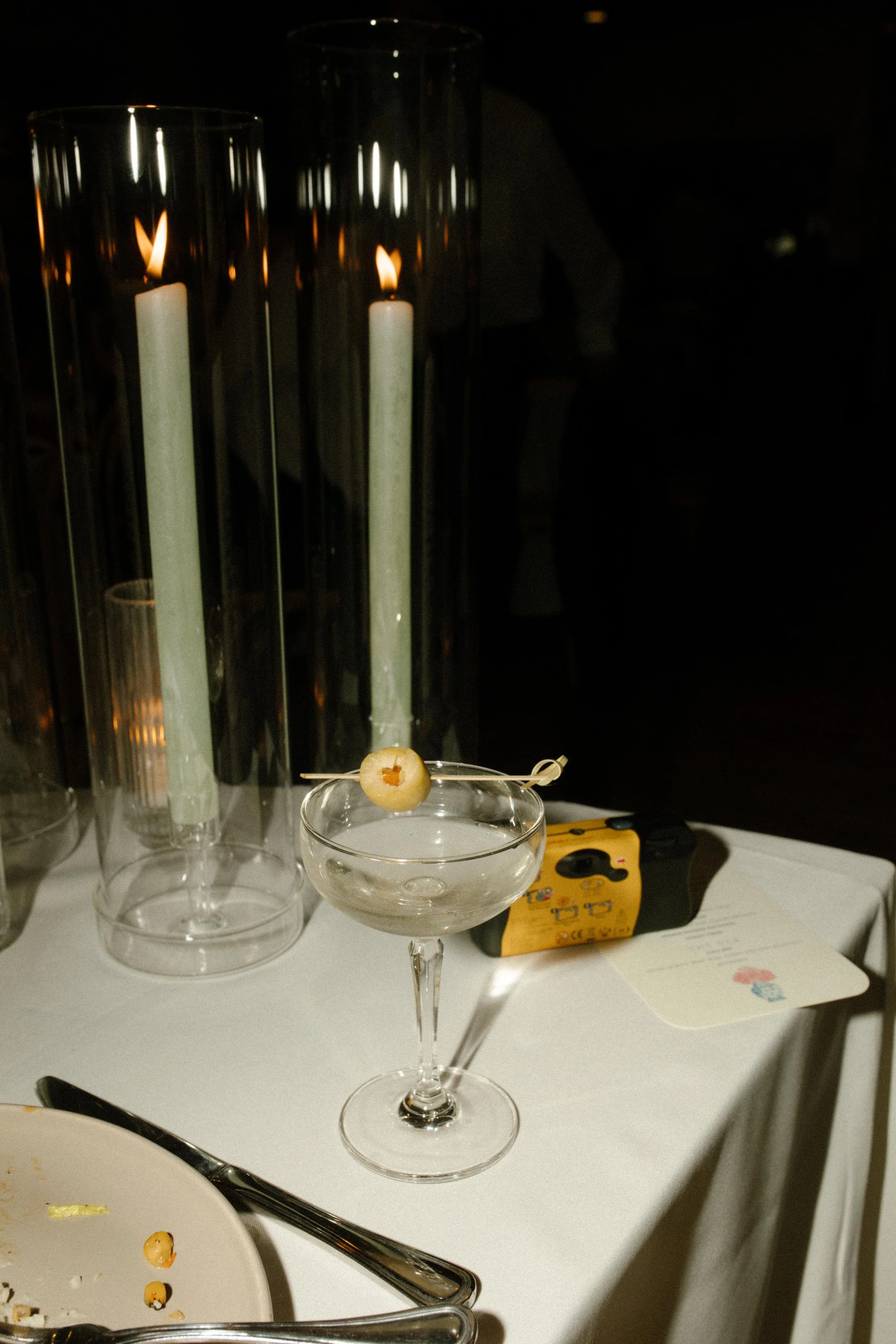 A single martini glass with an olive, candles glowing—reception details in full romance mode.