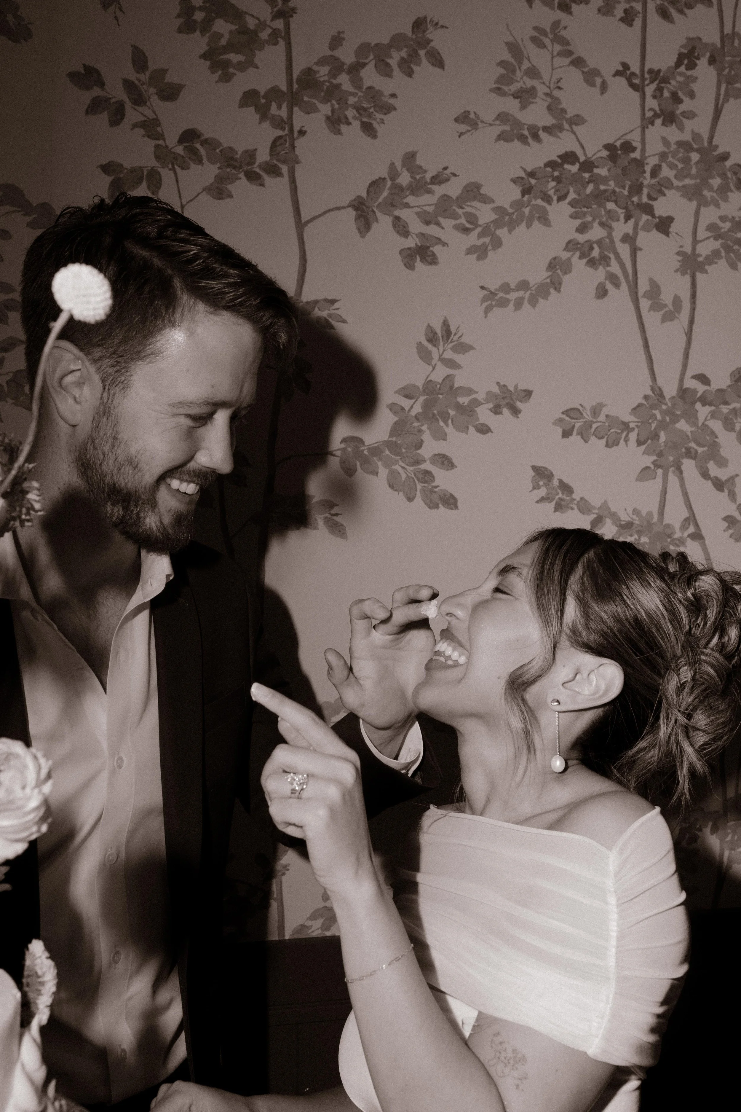 Groom feeding cake to bride as they laugh together.
