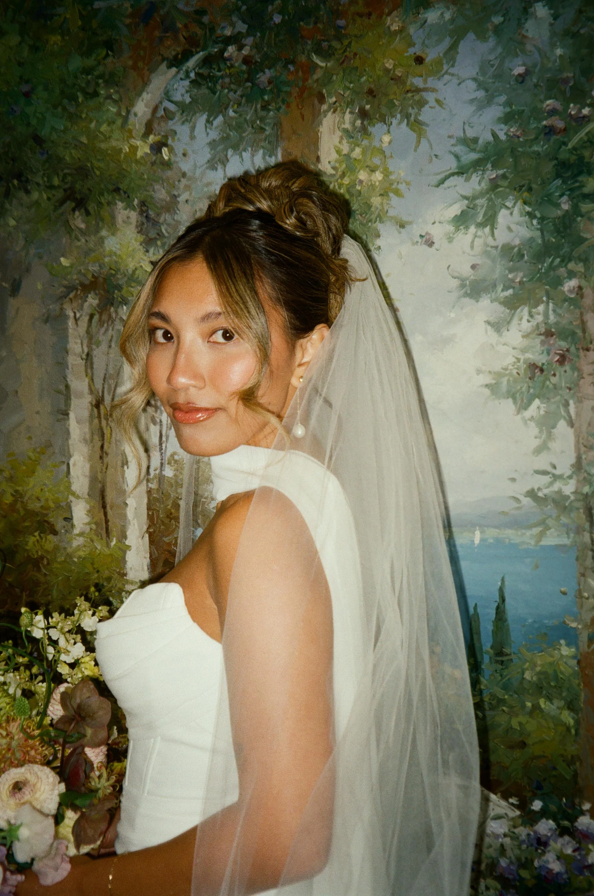 Bride posing in front of a hand-painted mural in her veil.
