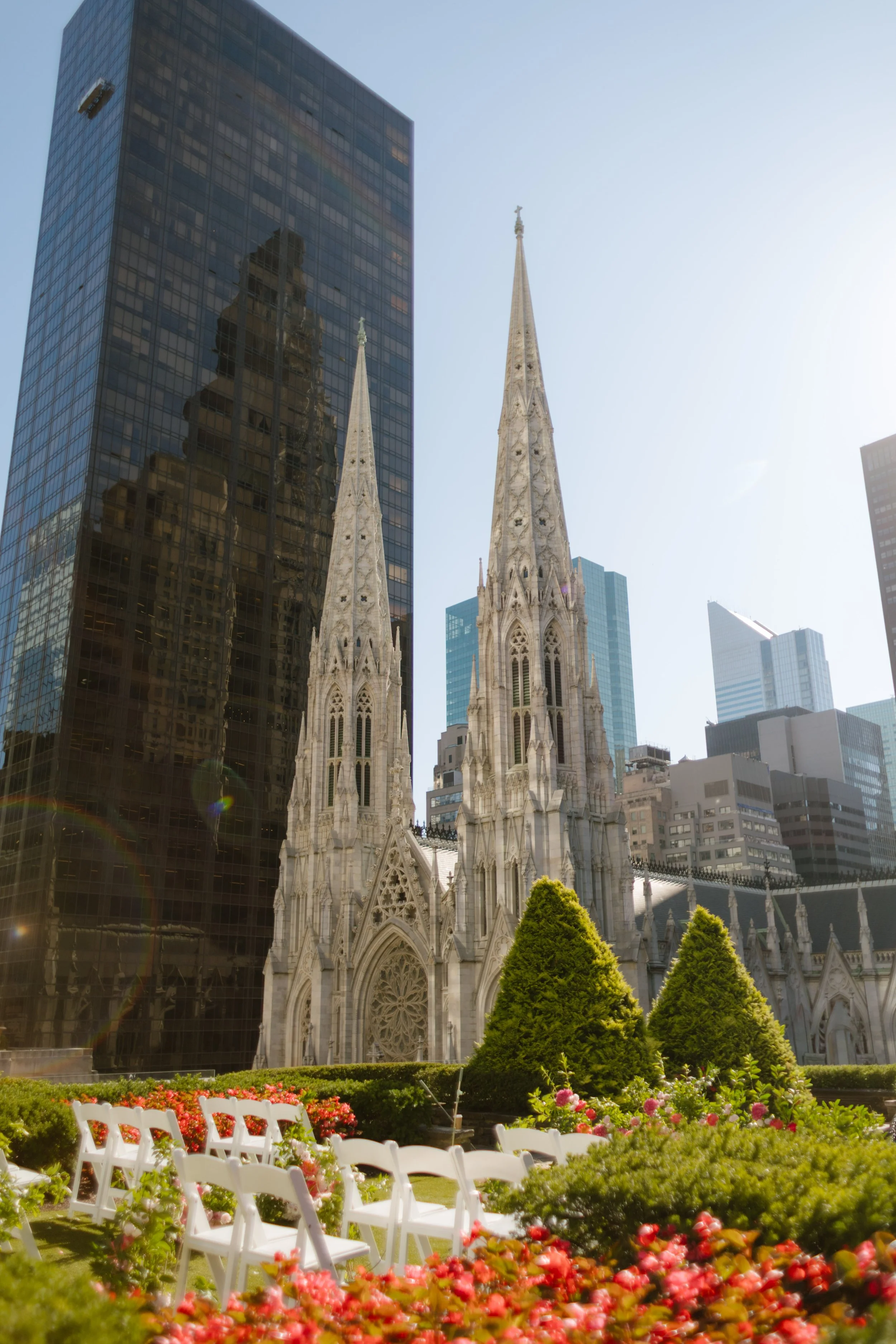 Rows of white chairs and blooming florals set against a backdrop of historic cathedral spires and modern skyscrapers—a picture-perfect ceremony for a wedding in New York City.