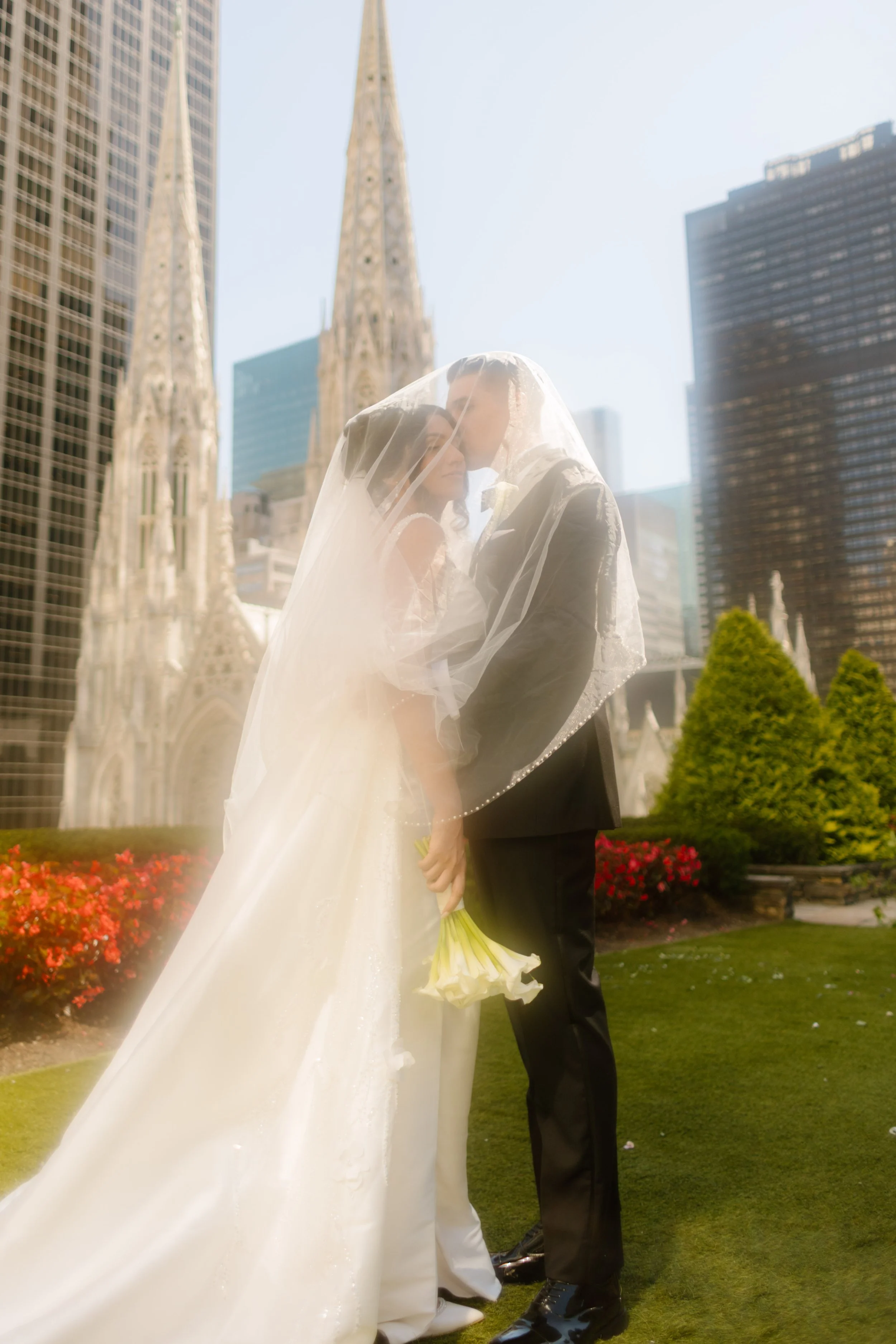 Bride and groom wrapped in her veil, forehead to forehead, soft light pouring through—St. Patrick’s Cathedral anchoring the magic of their wedding in New York City.
