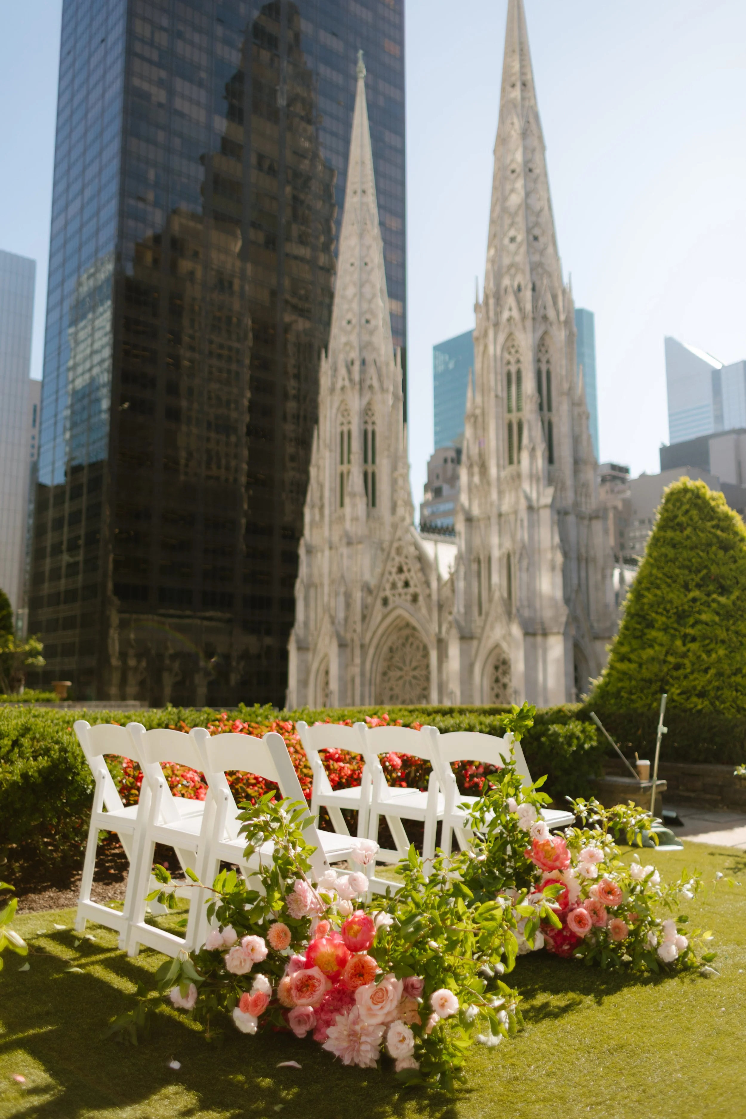 Rows of white chairs and lush floral arrangements glowing in the afternoon sun, waiting for guests to arrive—quiet anticipation before the rooftop wedding in New York City begins.