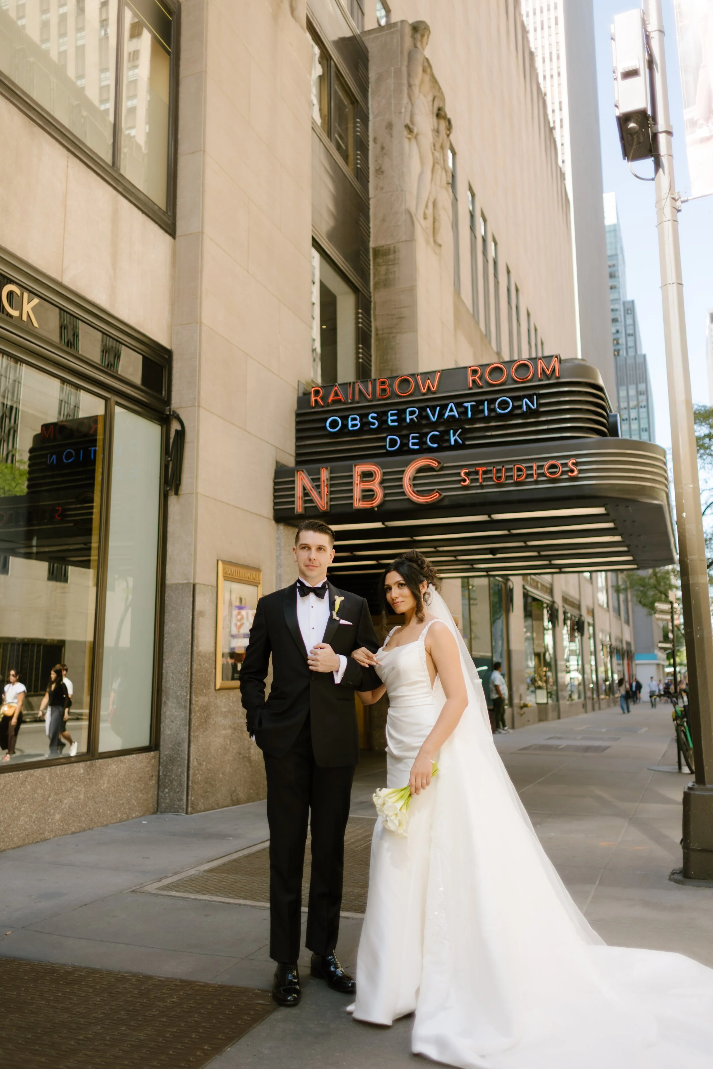 Bride and groom sharing a sweet moment outside the Rainbow Room and NBC Studios marquee—an iconic midtown stop during their wedding in New York City.