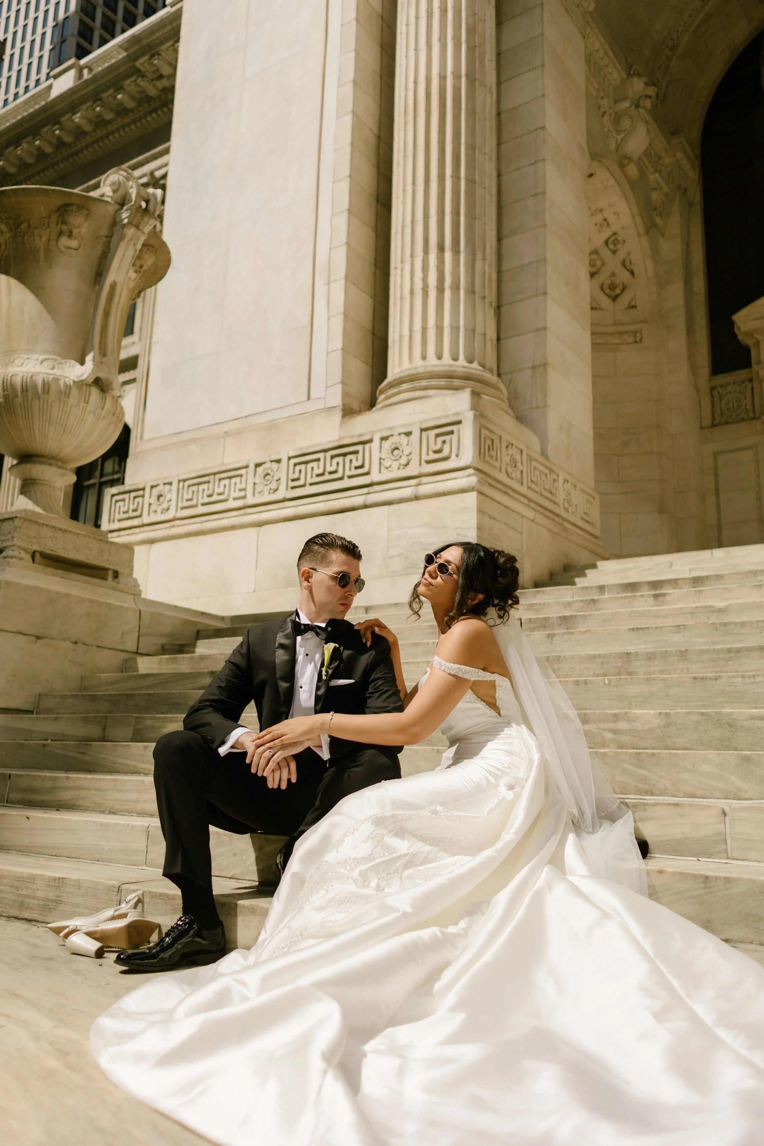 The couple lounges on the grand stone steps of the New York Public Library, sunglasses on and love loud