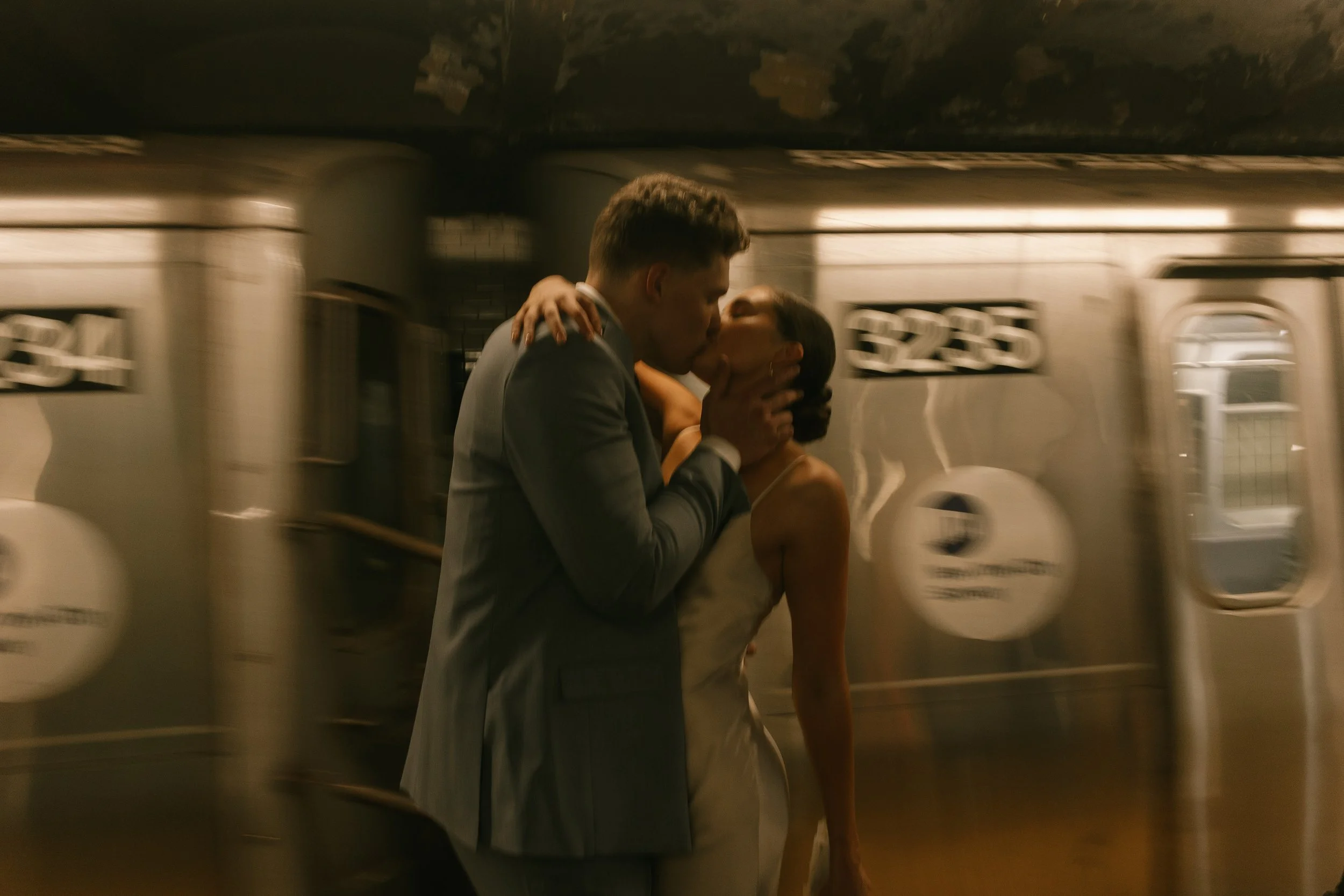A motion-blurred subway speeds by as this New York City elopement couple shares a passionate kiss on the platform.