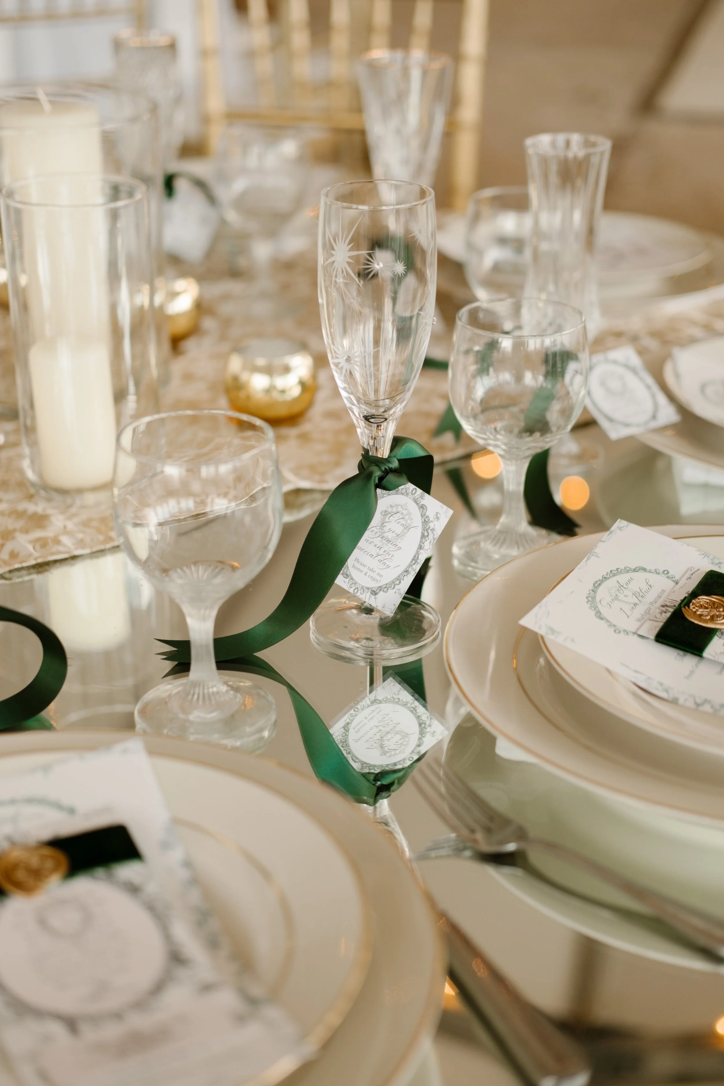 A romantic reception tablescape featuring champagne flutes, gold accents, and green ribbon-tied place cards at an Arkansas wedding.