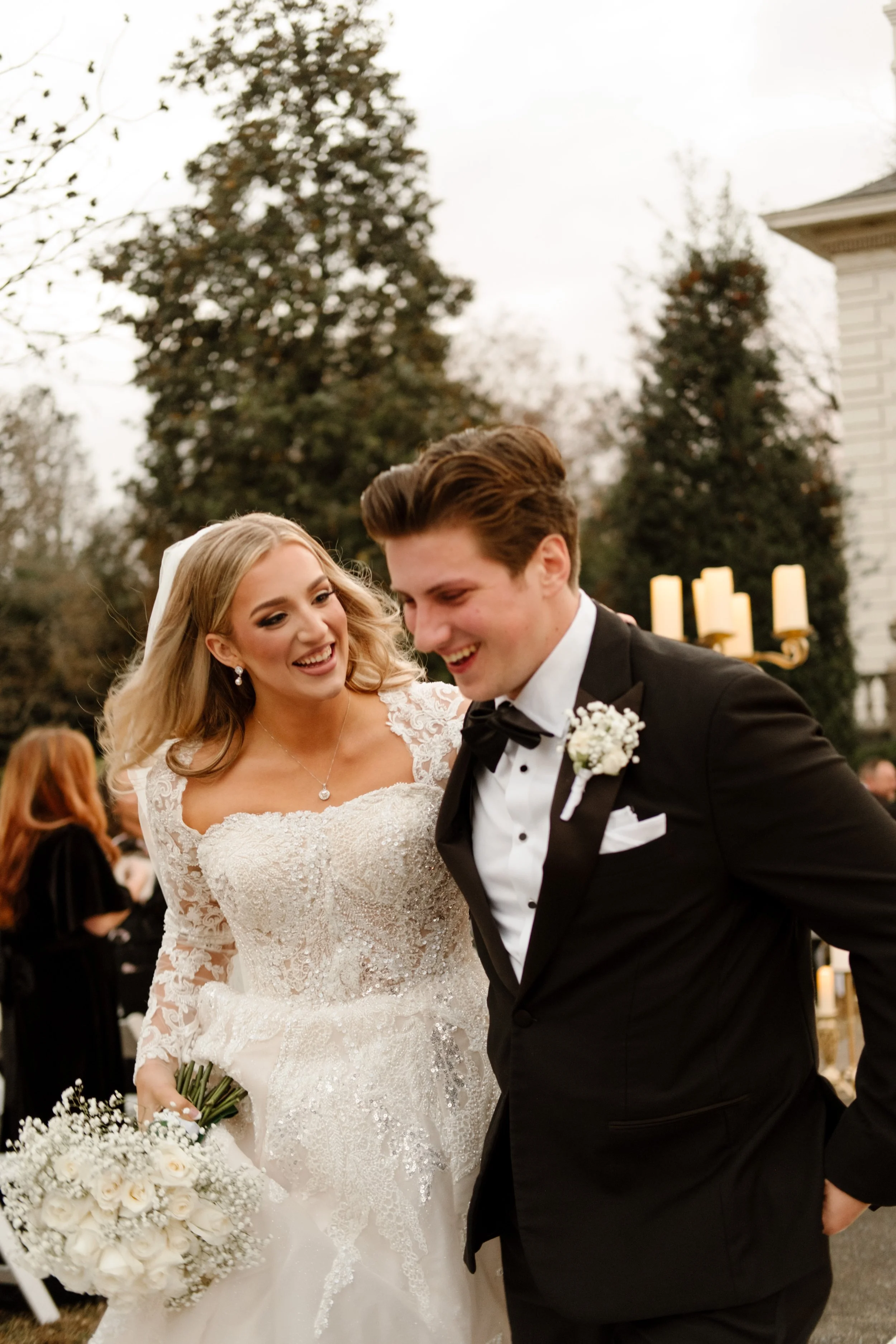 Just married bliss—bride and groom beam as they walk together, bouquet in hand and love all over their faces.