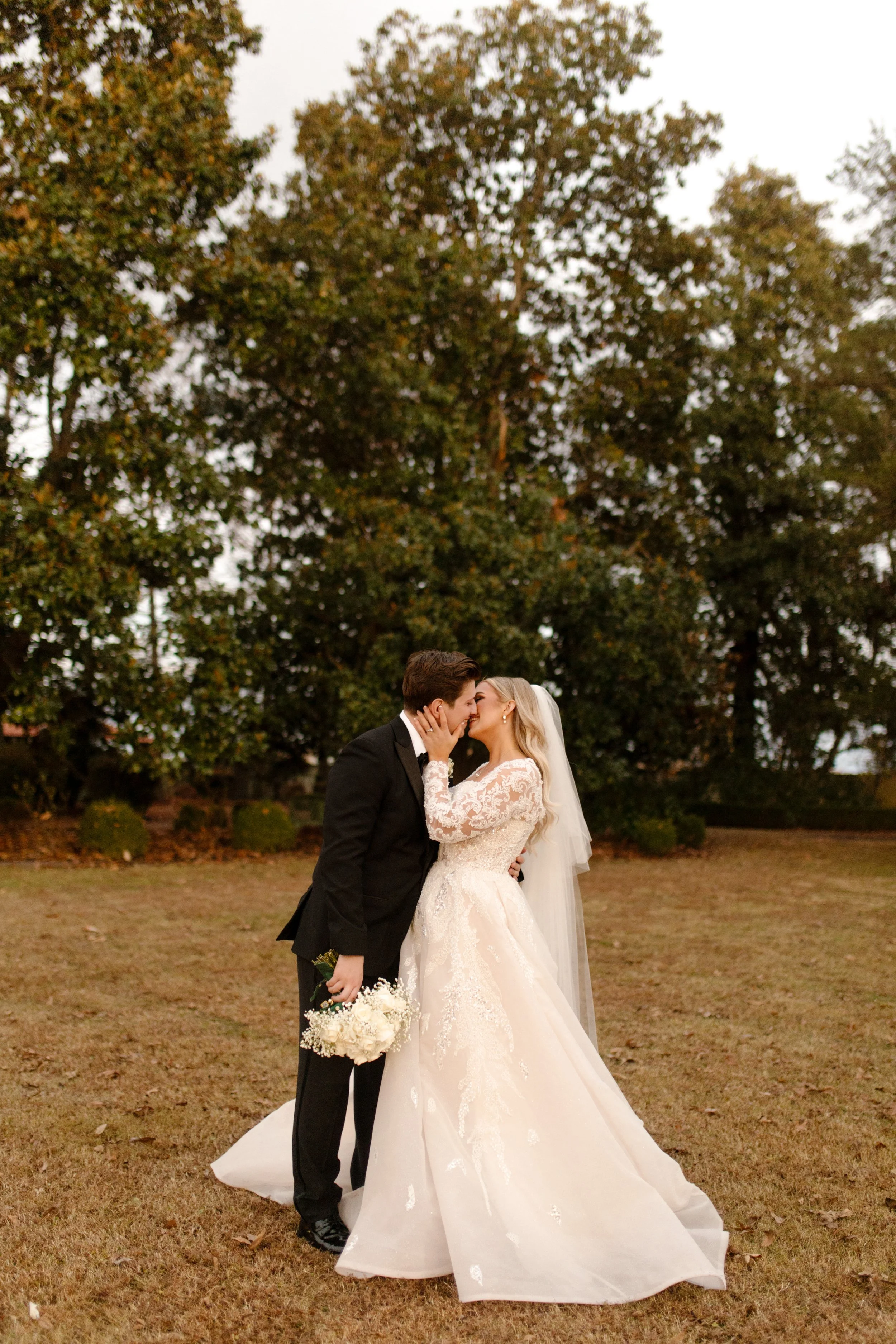 Bride and groom share a slow, full kiss under golden skies in a quiet field, soaking in the calm after their Arkansas wedding vows.
