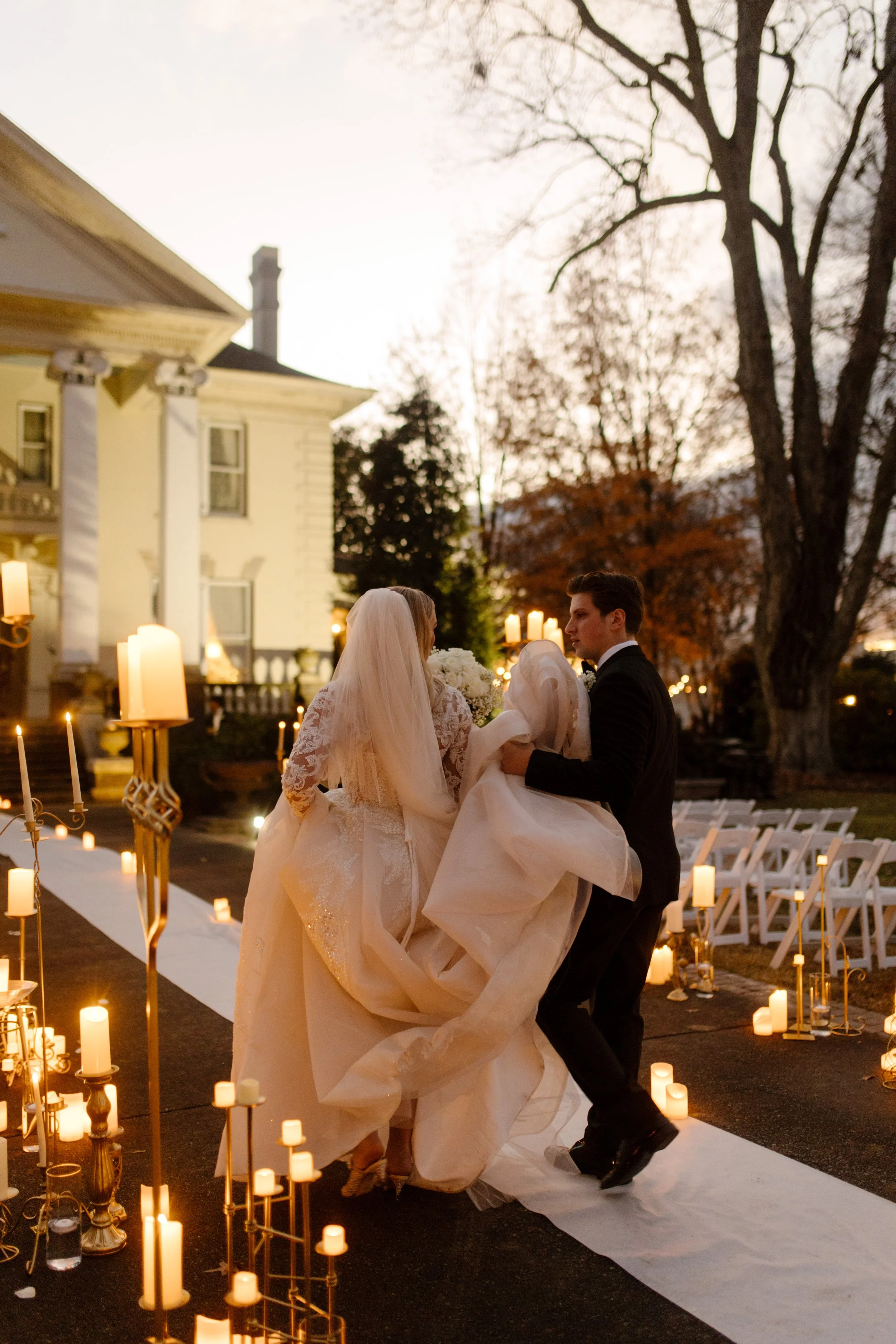 Just married and glowing, the couple walks hand-in-hand down the candlelit aisle at their Arkansas wedding as golden hour spills over the scene.