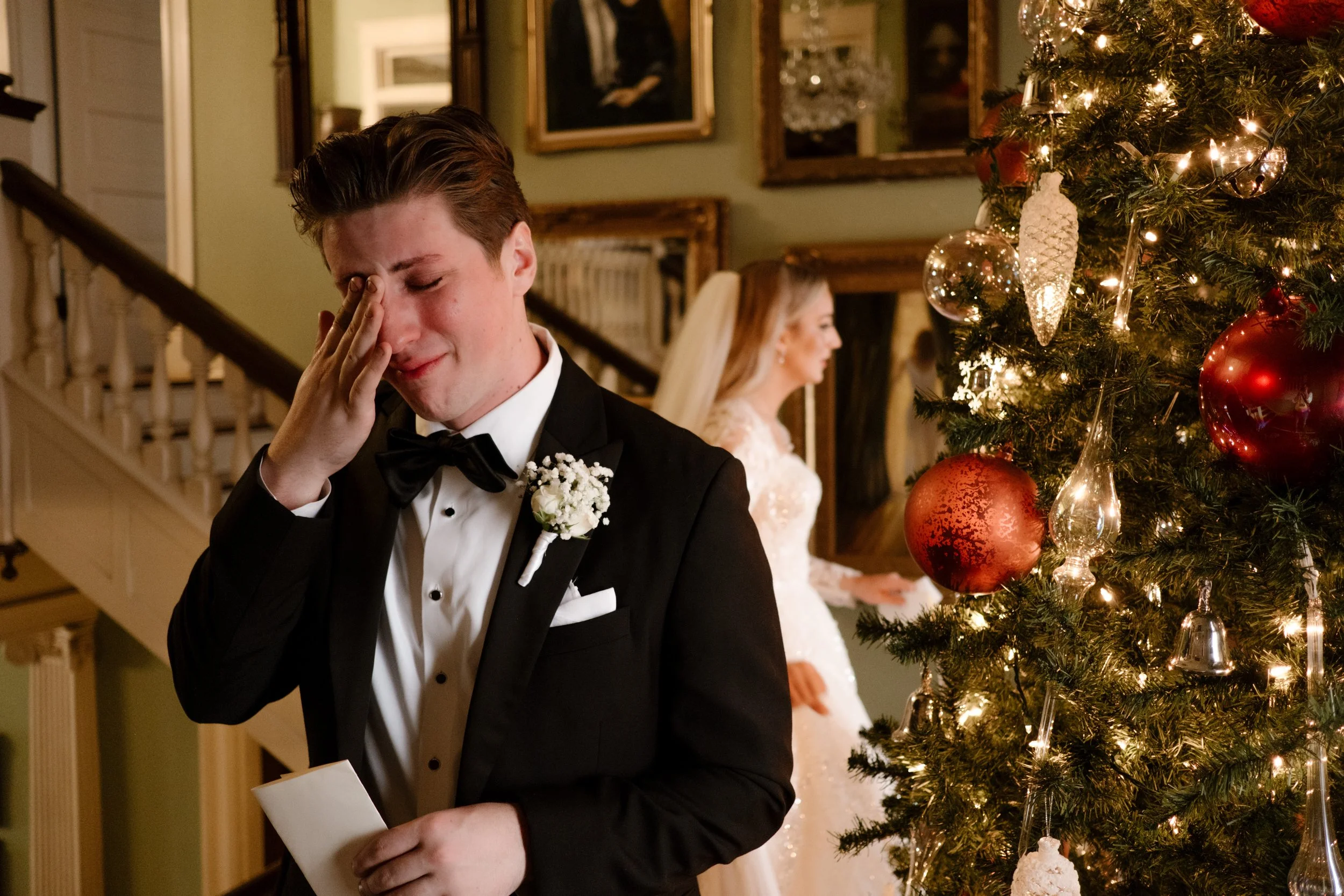 Groom gets emotional reading a note from his bride near the Christmas tree, just before the ceremony begins at their Arkansas wedding.