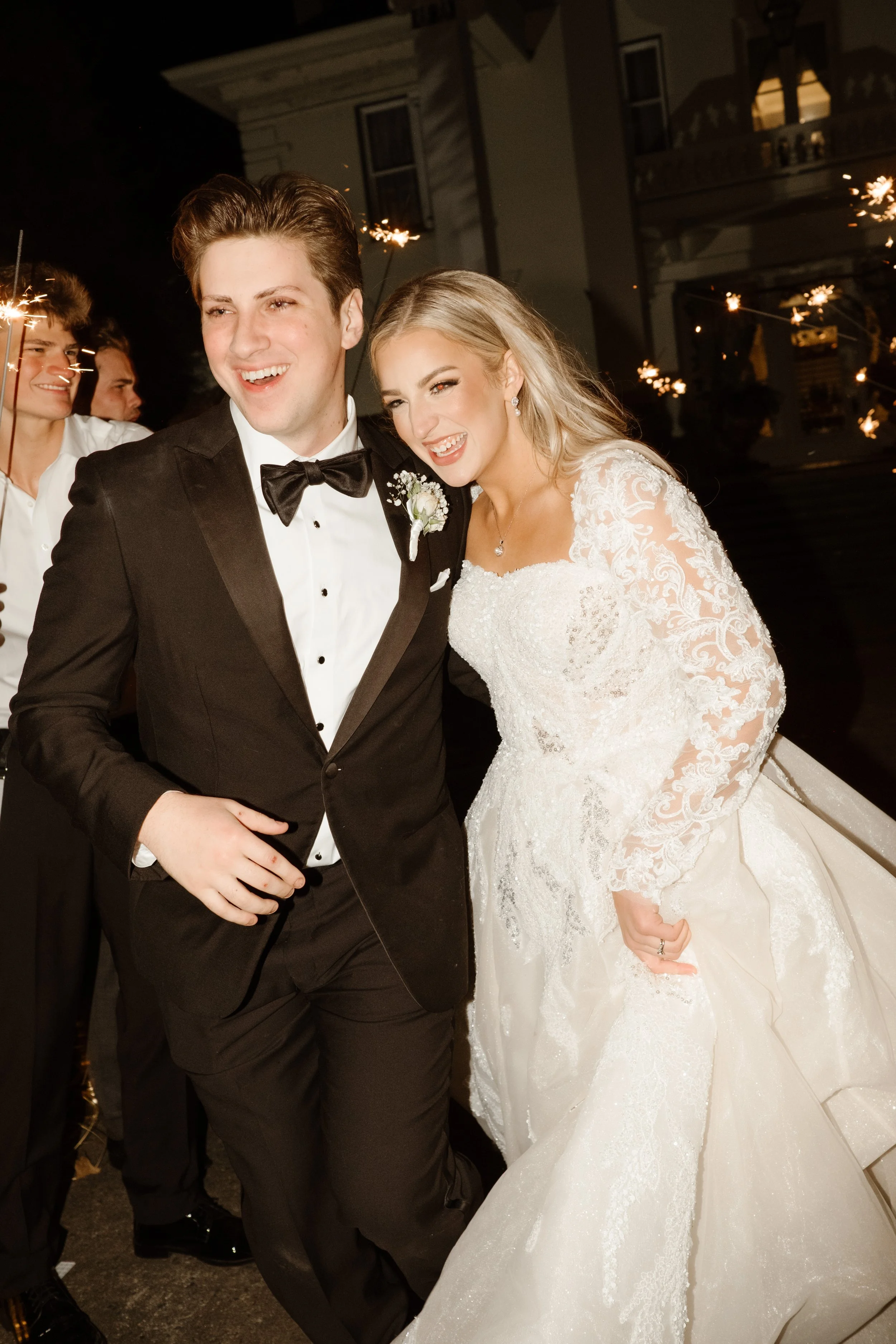 Bride and groom laugh and run through a sparkler exit, lit up with joy and golden light at the end of their Arkansas wedding celebration.