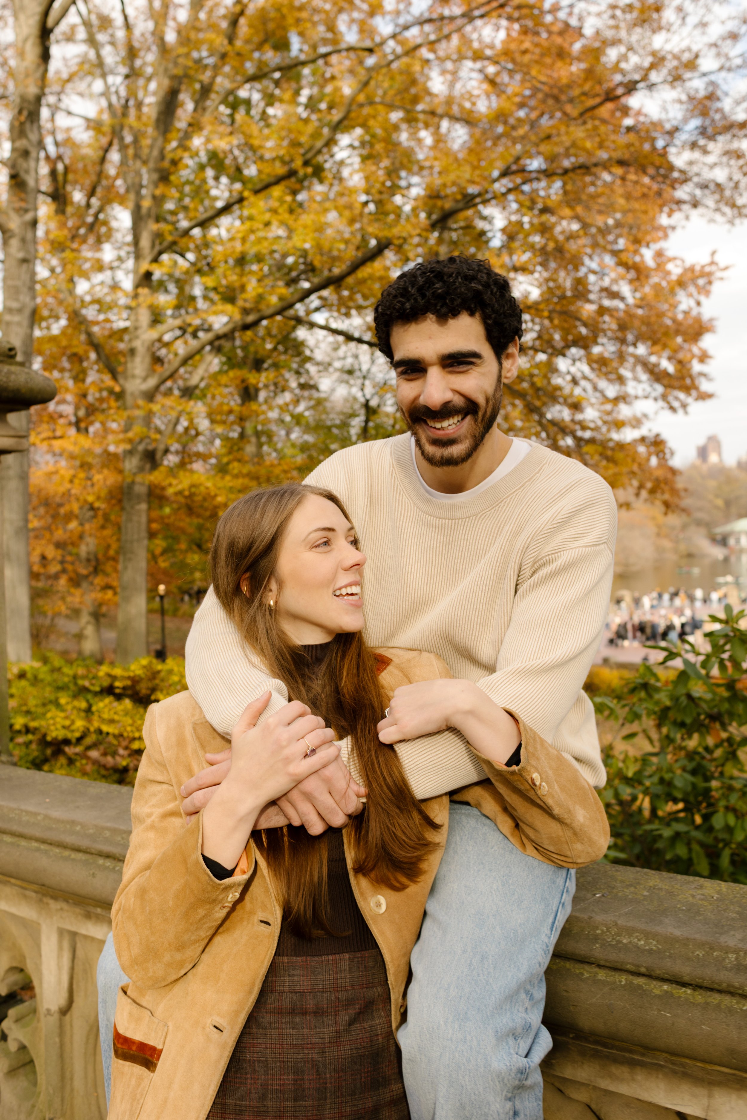 Cozy embrace on the stone railing near Bethesda Terrace during a golden-hour Central Park photoshoot.