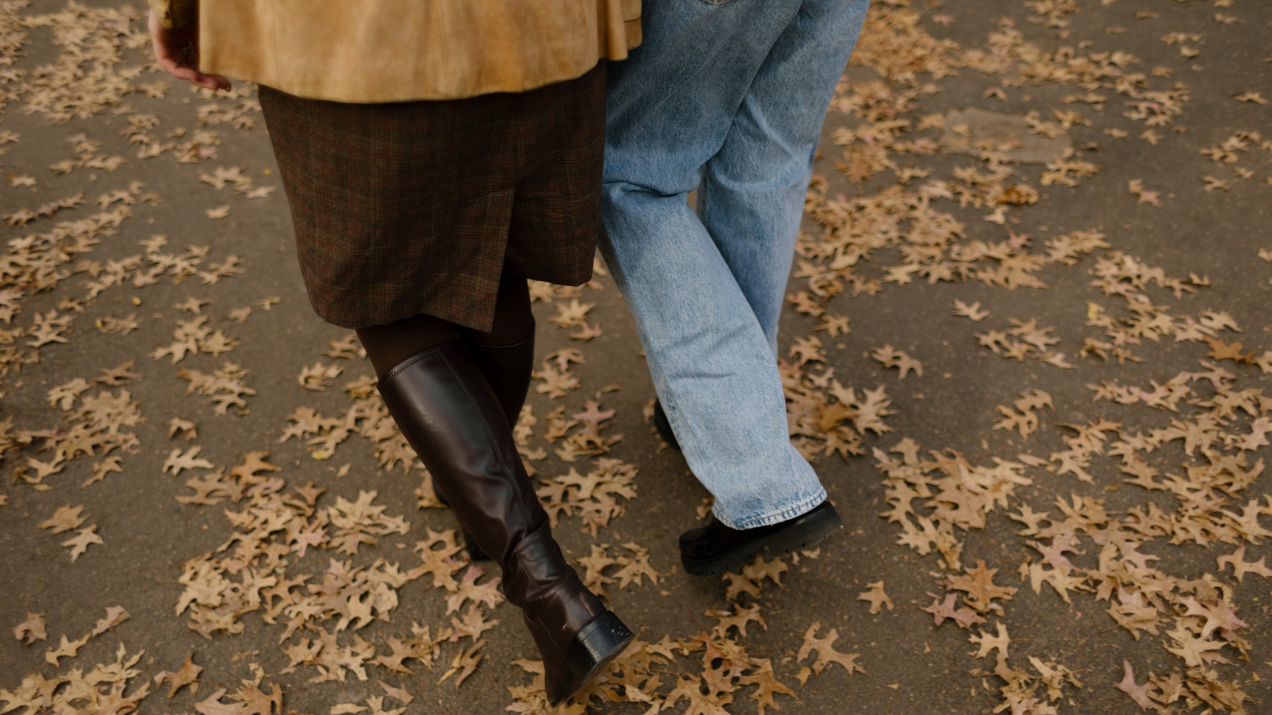 Detail shot of a couple walking side by side through fallen leaves in Central Park.