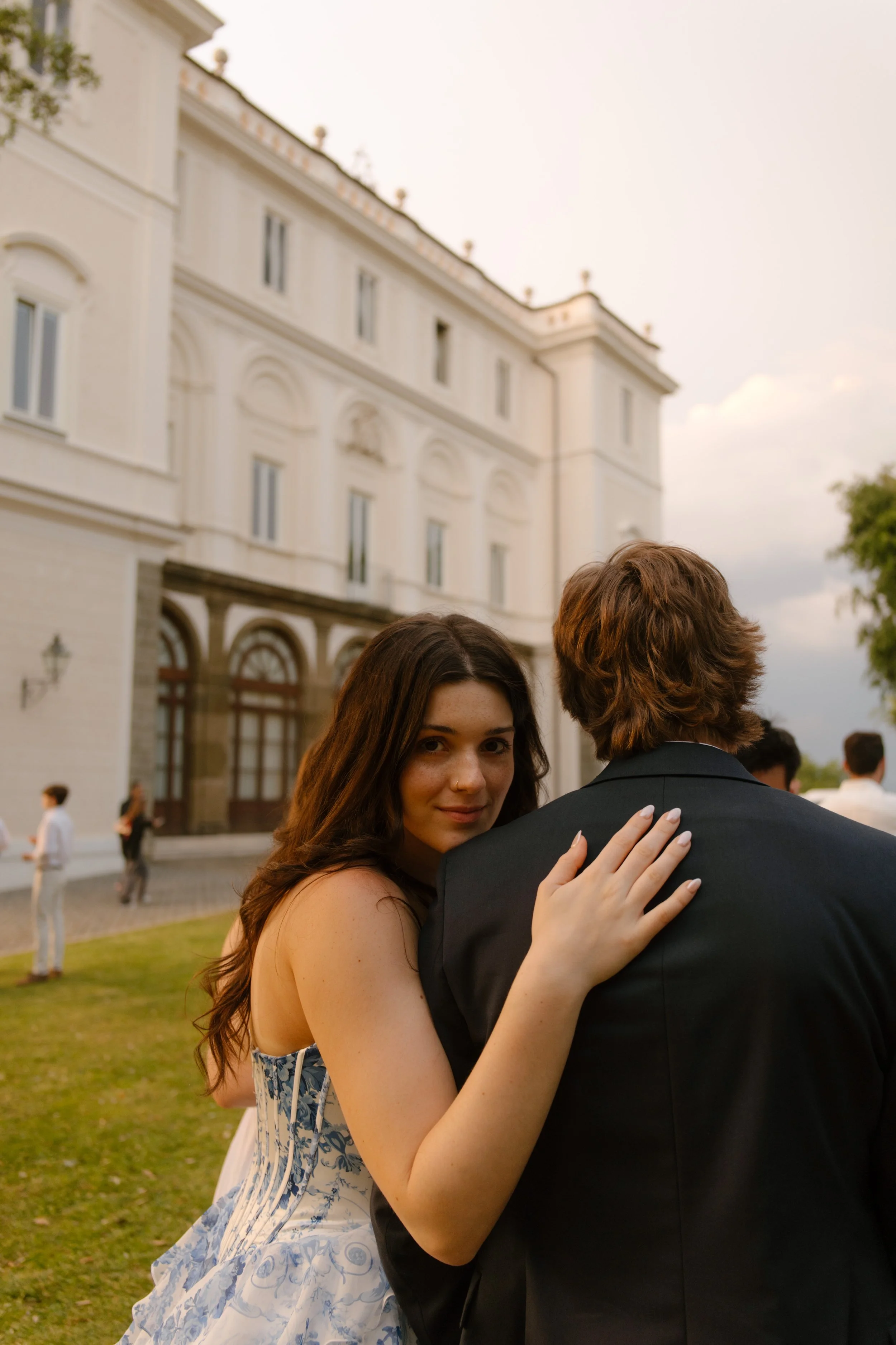 Bride looking over groom's shoulder while hugging him and smiling at camera. 