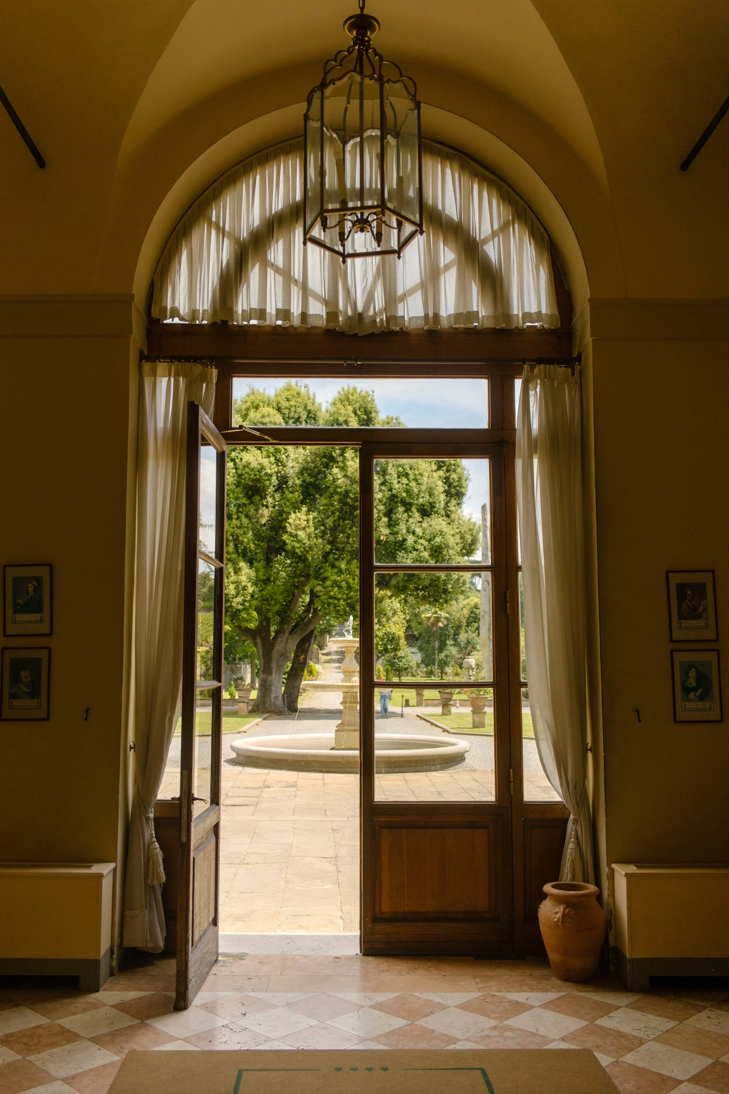 Arched door view into Italian garden before wedding rehearsal dinner. 