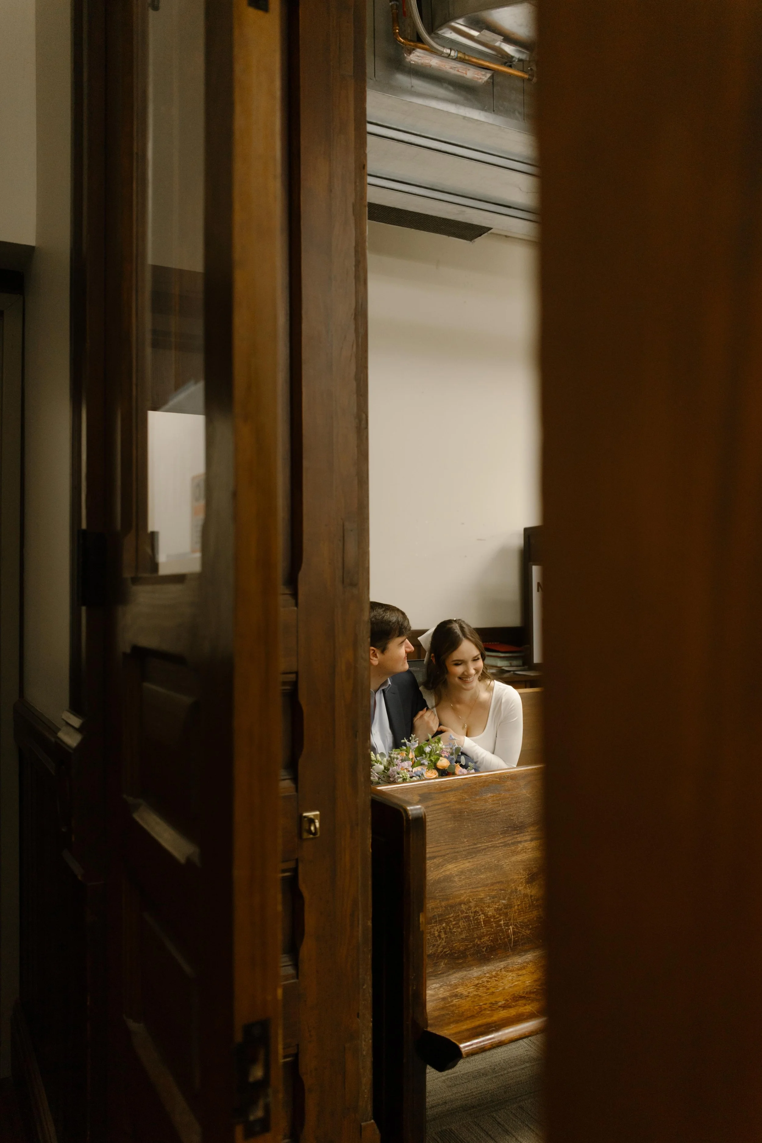 The couple shares a private, joyful moment while seated together on a wooden bench inside the Knoxville courthouse.