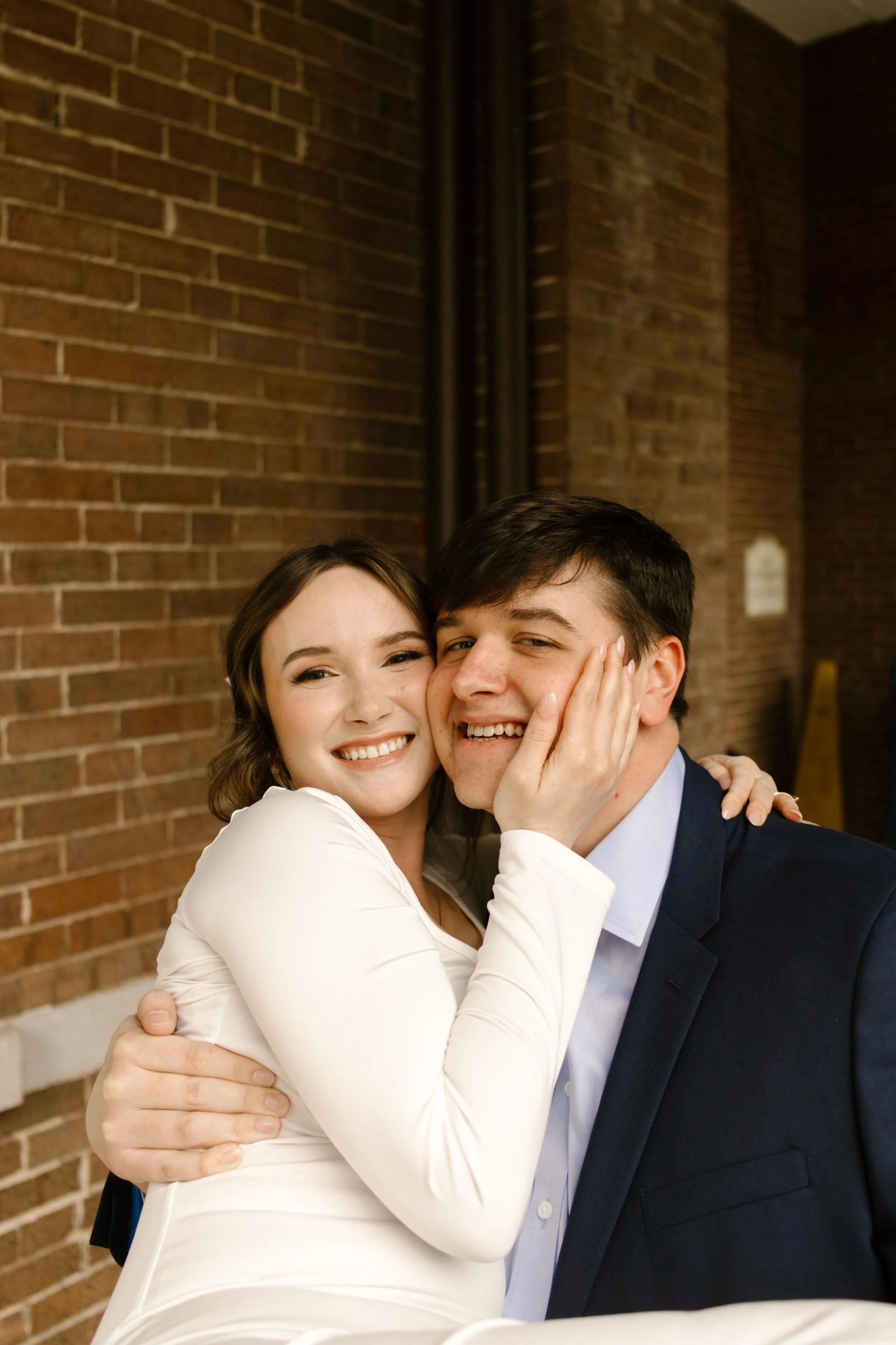 The bride and groom share a tight, happy embrace, cheek to cheek, with big smiles and post-ceremony bliss radiating from them.