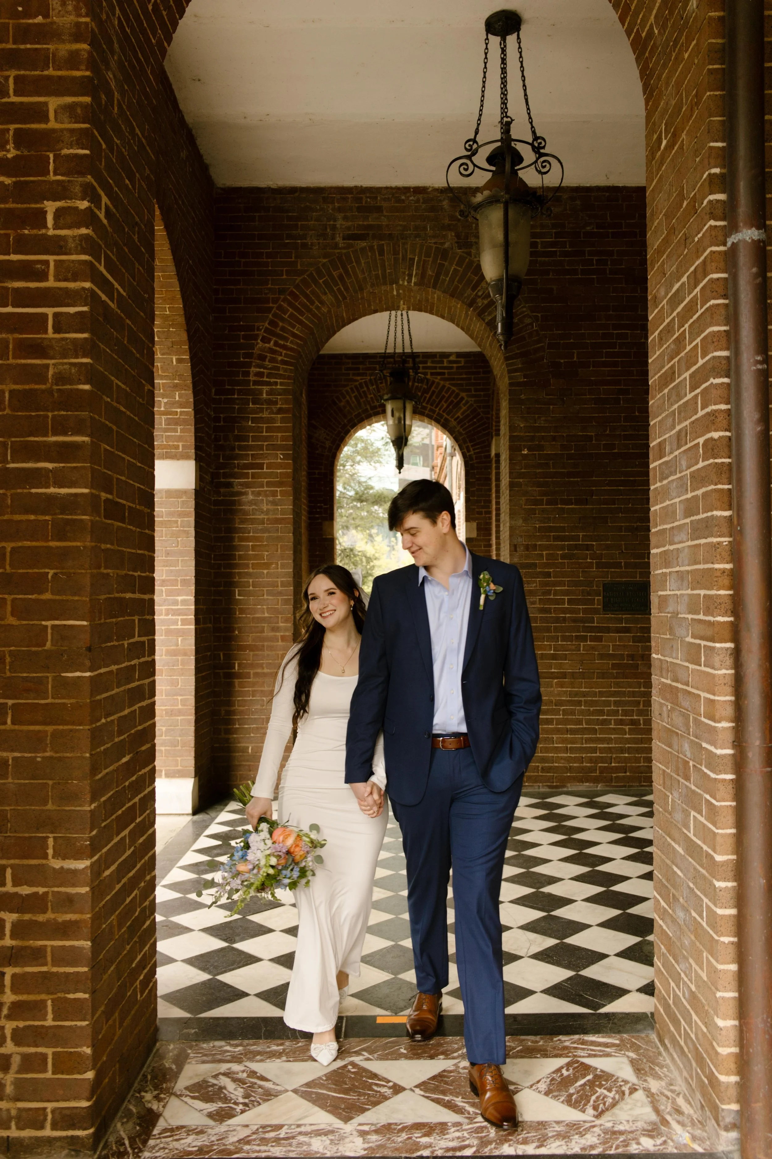 Walking hand-in-hand through the courthouse corridor, the couple beams at each other, bouquet swinging and hearts wide open.