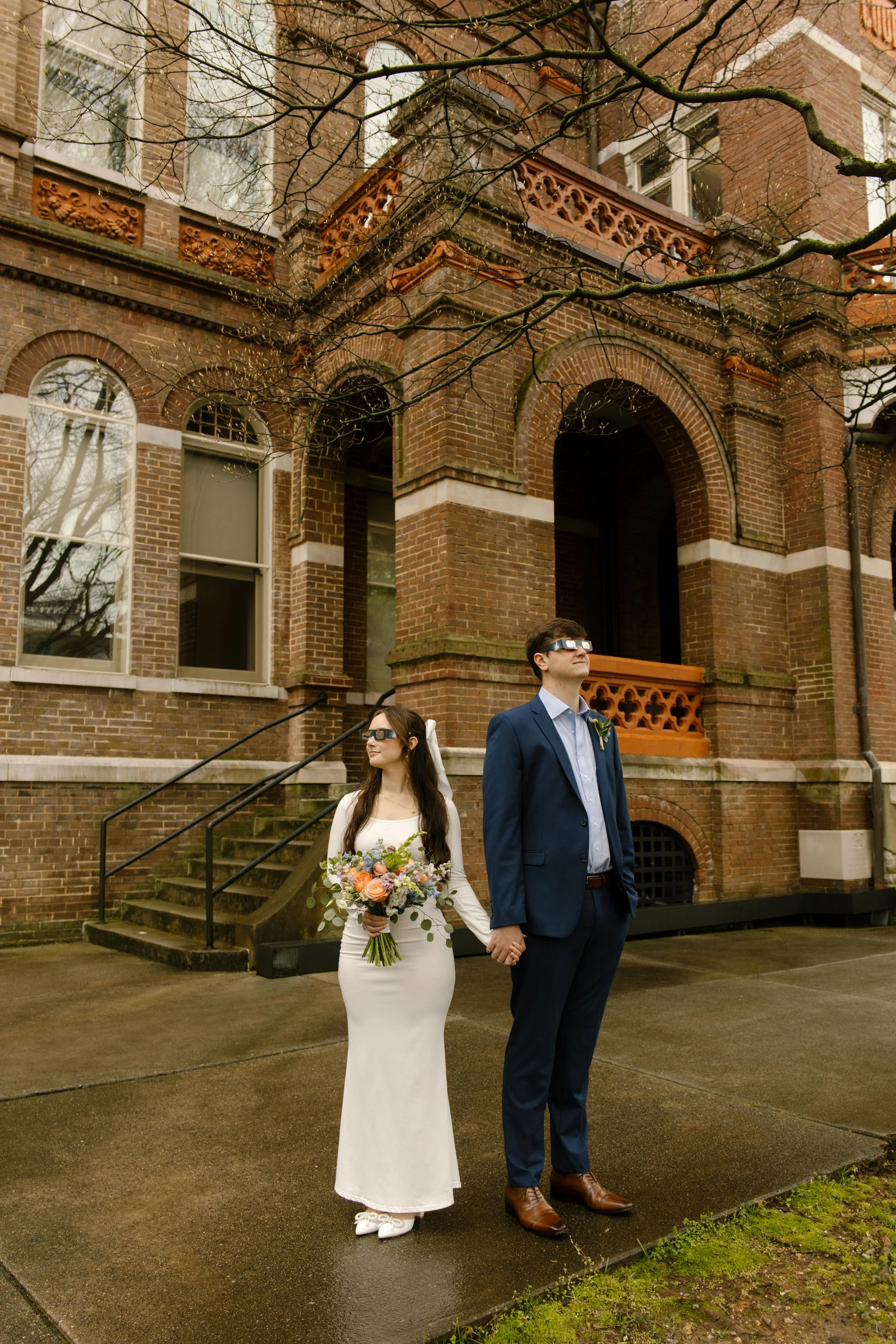 Holding hands in front of the historic brick building, the newlyweds wear matching sunglasses and strike a fun, rebellious pose during their Knoxville courthouse elopement.