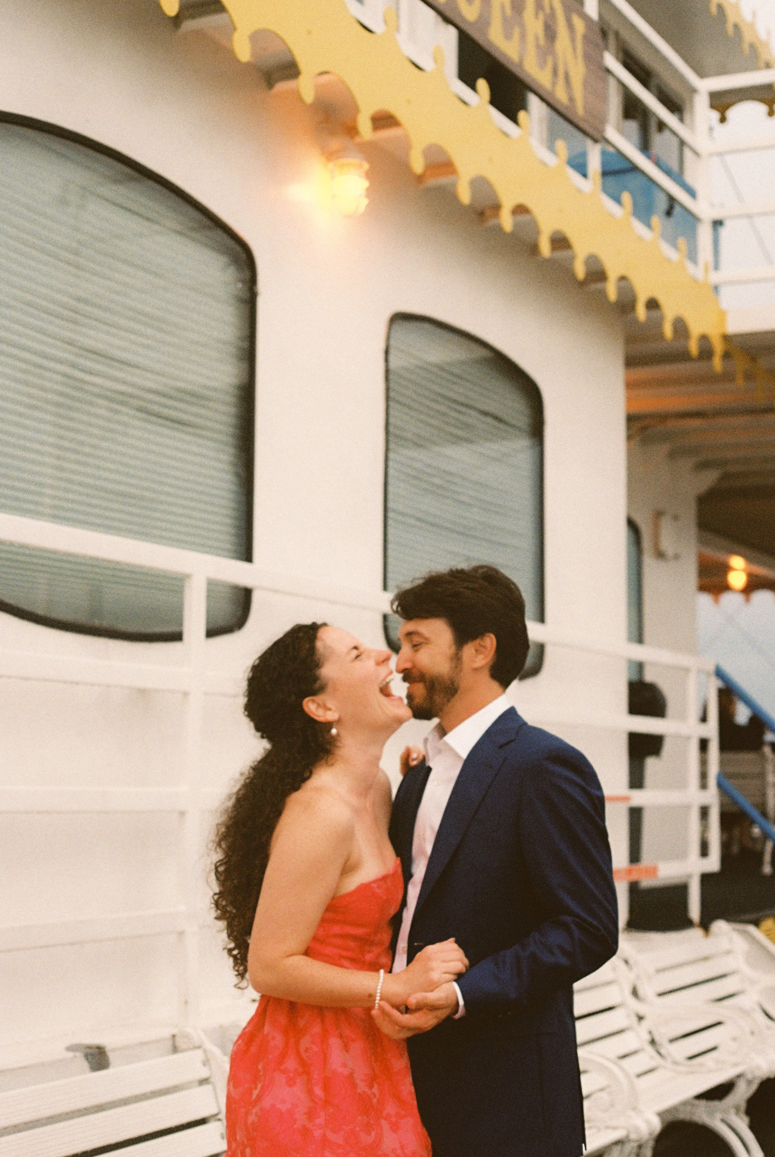 Bride laughing with her partner on the deck of the Creole Queen, a quiet moment during their New Orleans wedding celebration.