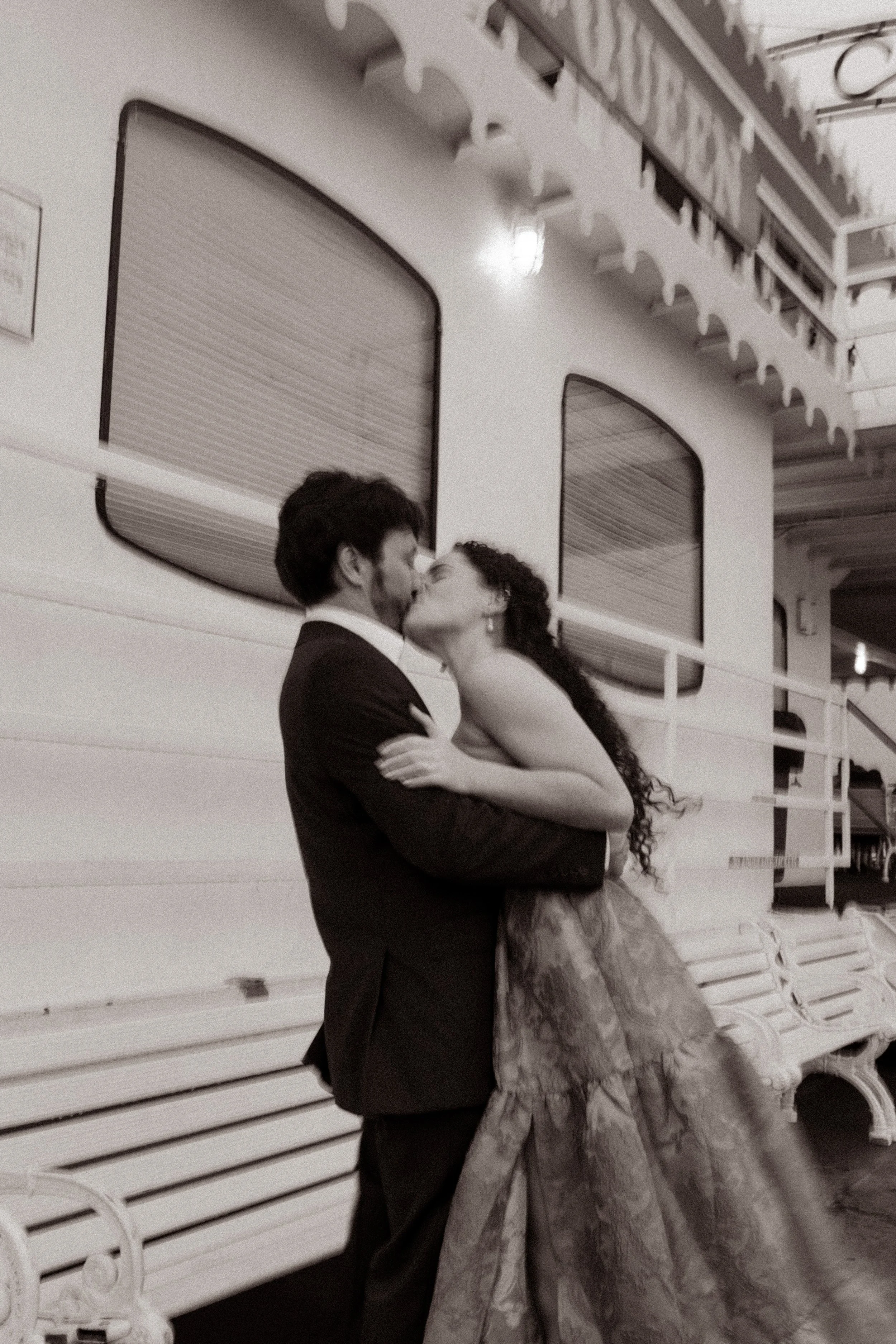 Black and white photo of the couple kissing on the riverboat, wrapped in each other during their New Orleans wedding weekend.