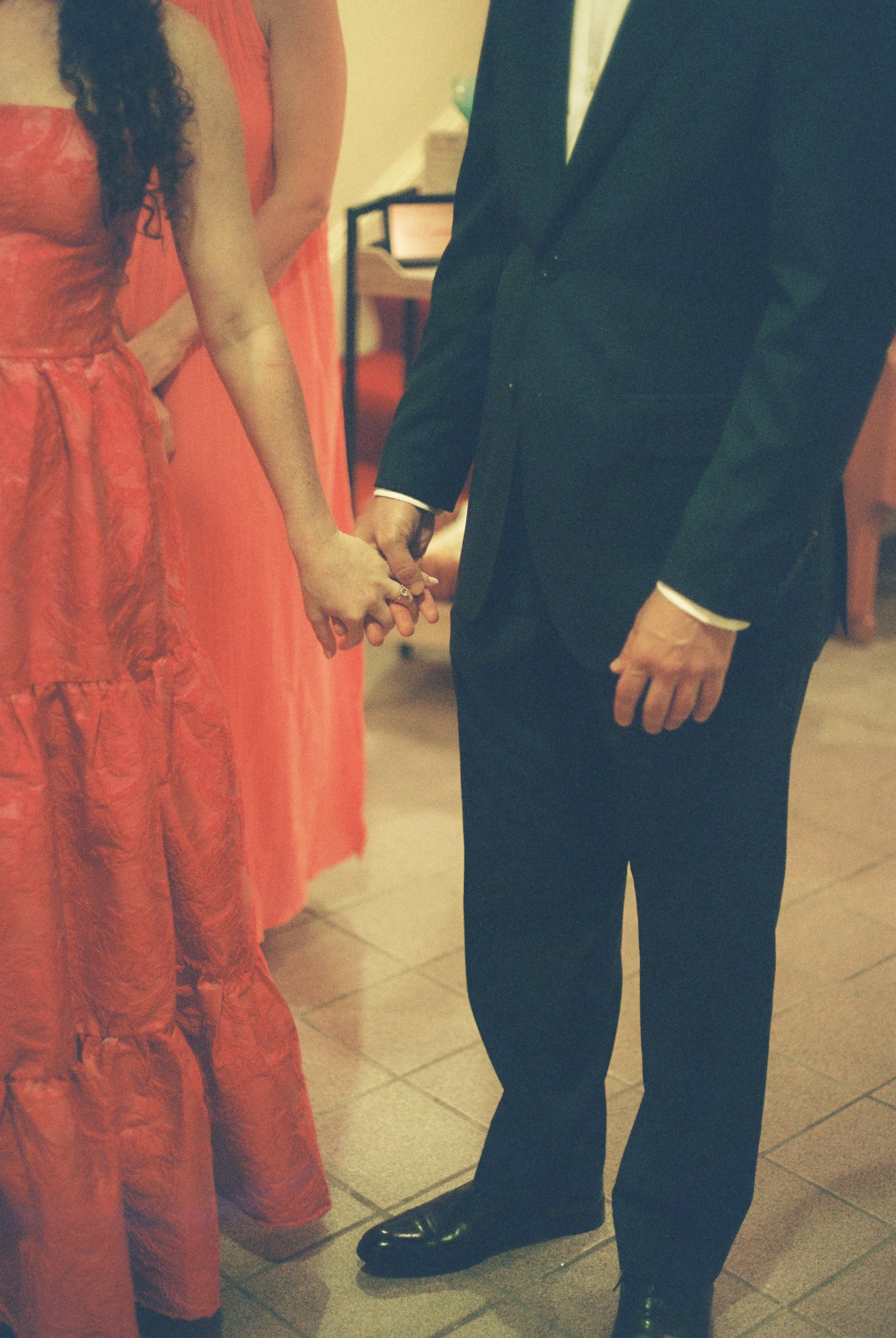 The bride and groom holding hands, captured in a soft, grainy film frame before the celebration begins.