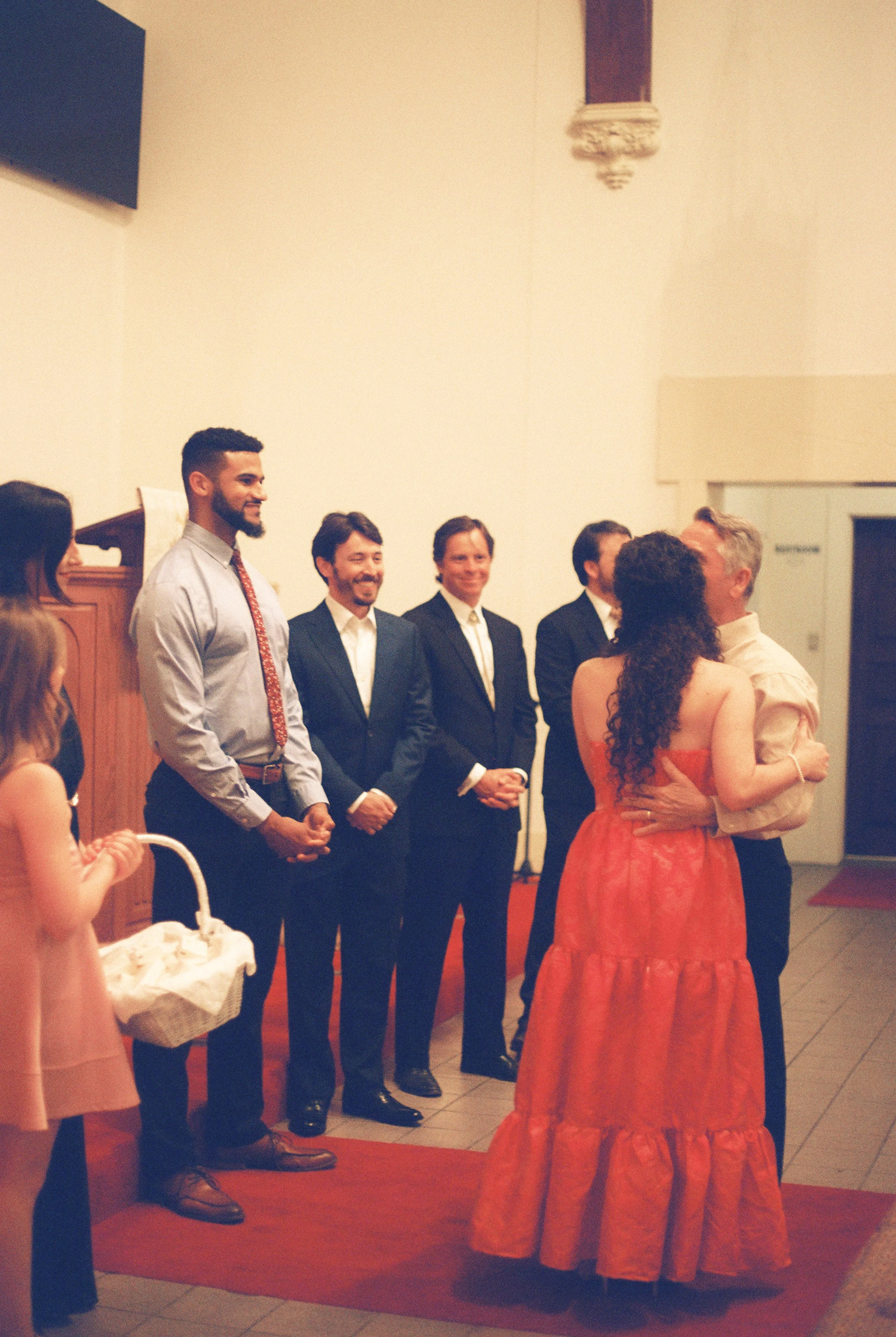 Wedding rehearsal moment inside the church, with the couple surrounded by their wedding party and family.