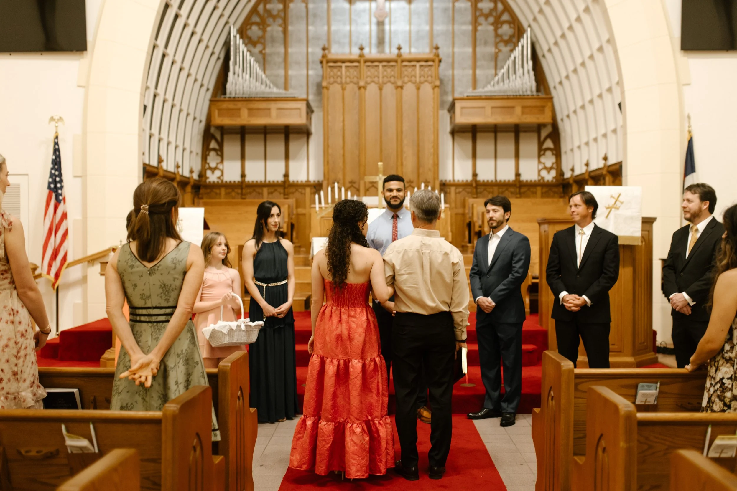 Bride standing at the altar during the wedding rehearsal, surrounded by loved ones inside a historic New Orleans church.
