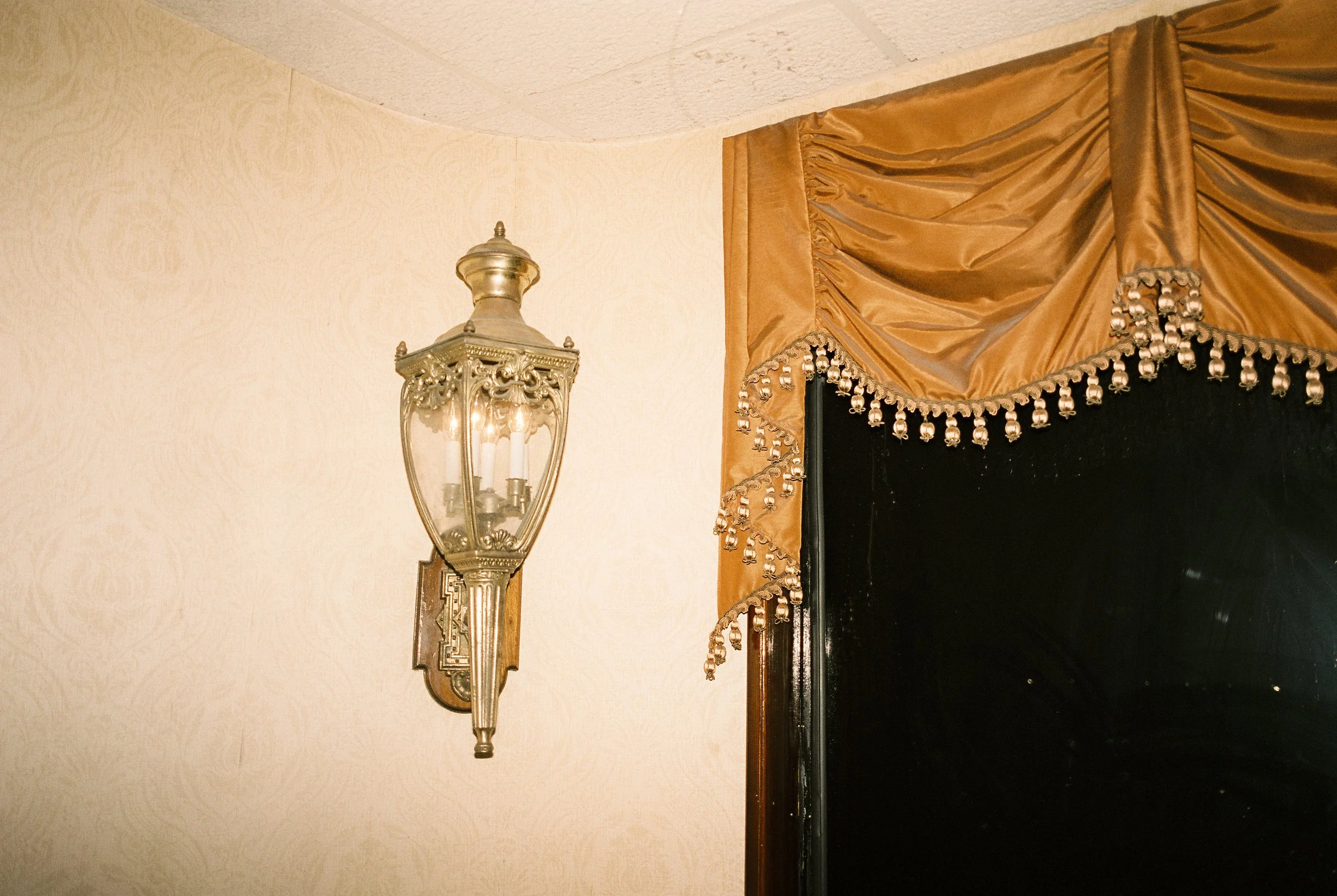 Vintage sconce and velvet drapery detail inside the riverboat—warm tones and old-world charm at a wedding reception.