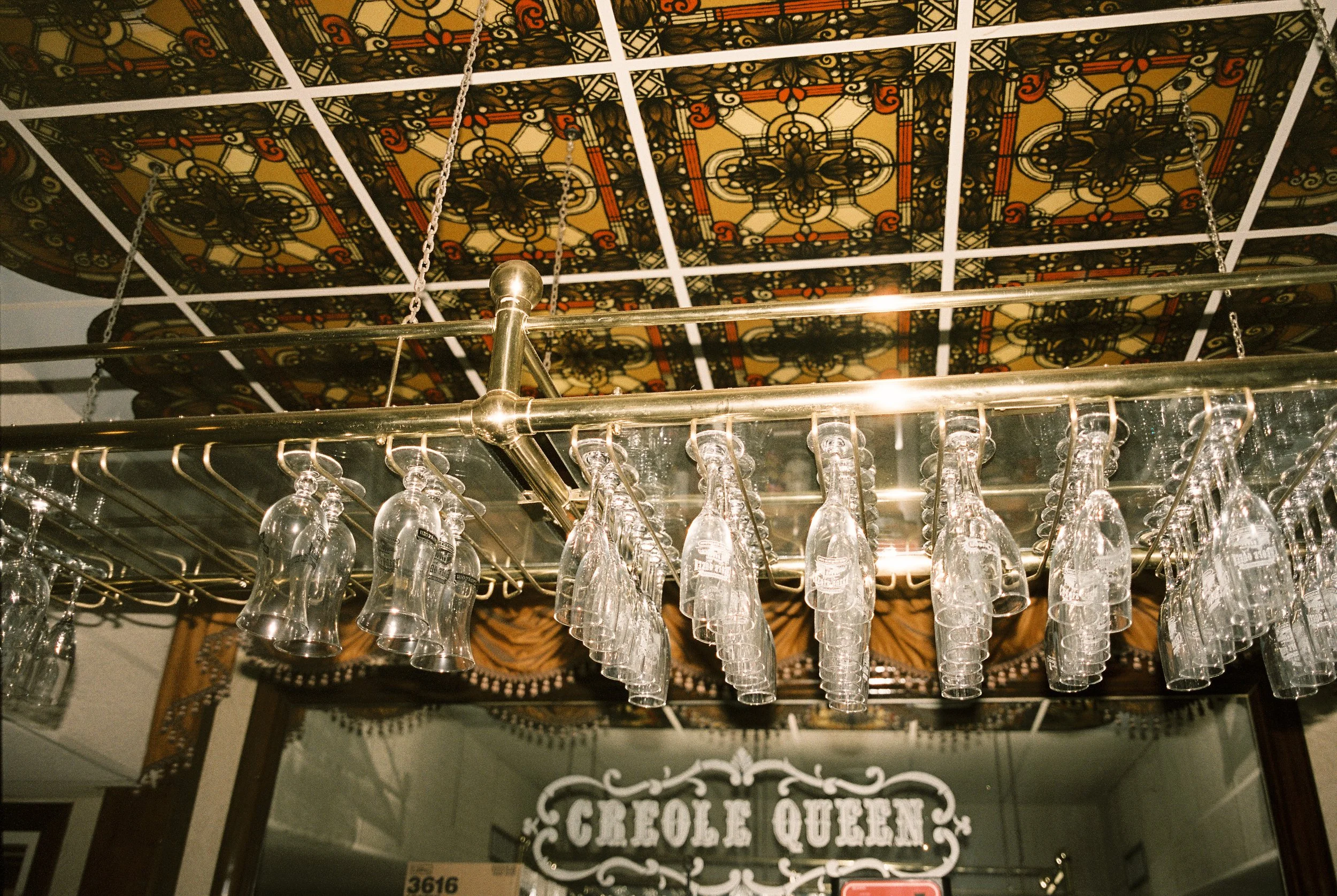 Glasses hanging over a mirrored bar beneath a stained-glass ceiling on the Creole Queen—classic New Orleans wedding vibes.