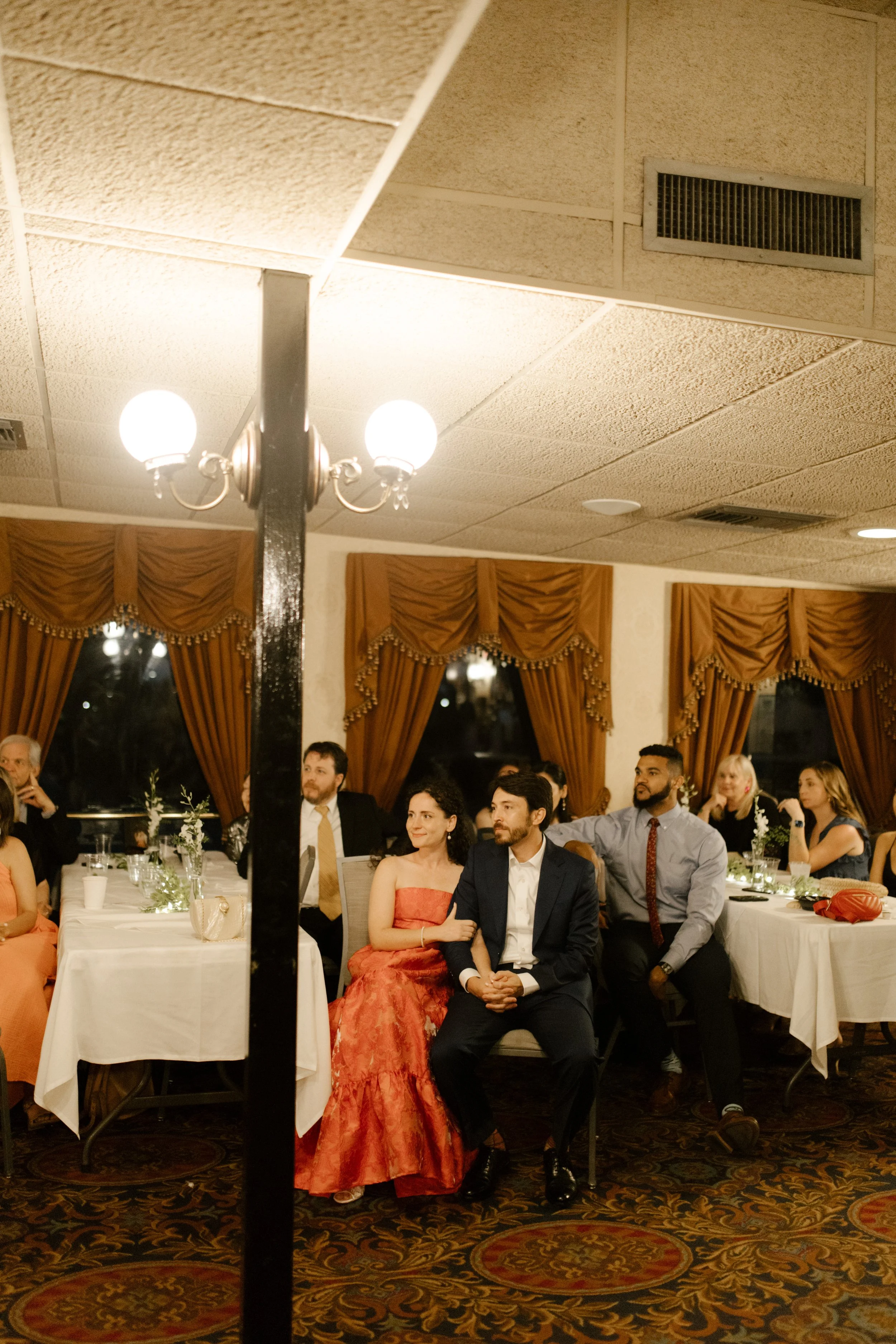 Guests seated around candlelit tables as the couple listens to a heartfelt speech during their New Orleans wedding welcome dinner.